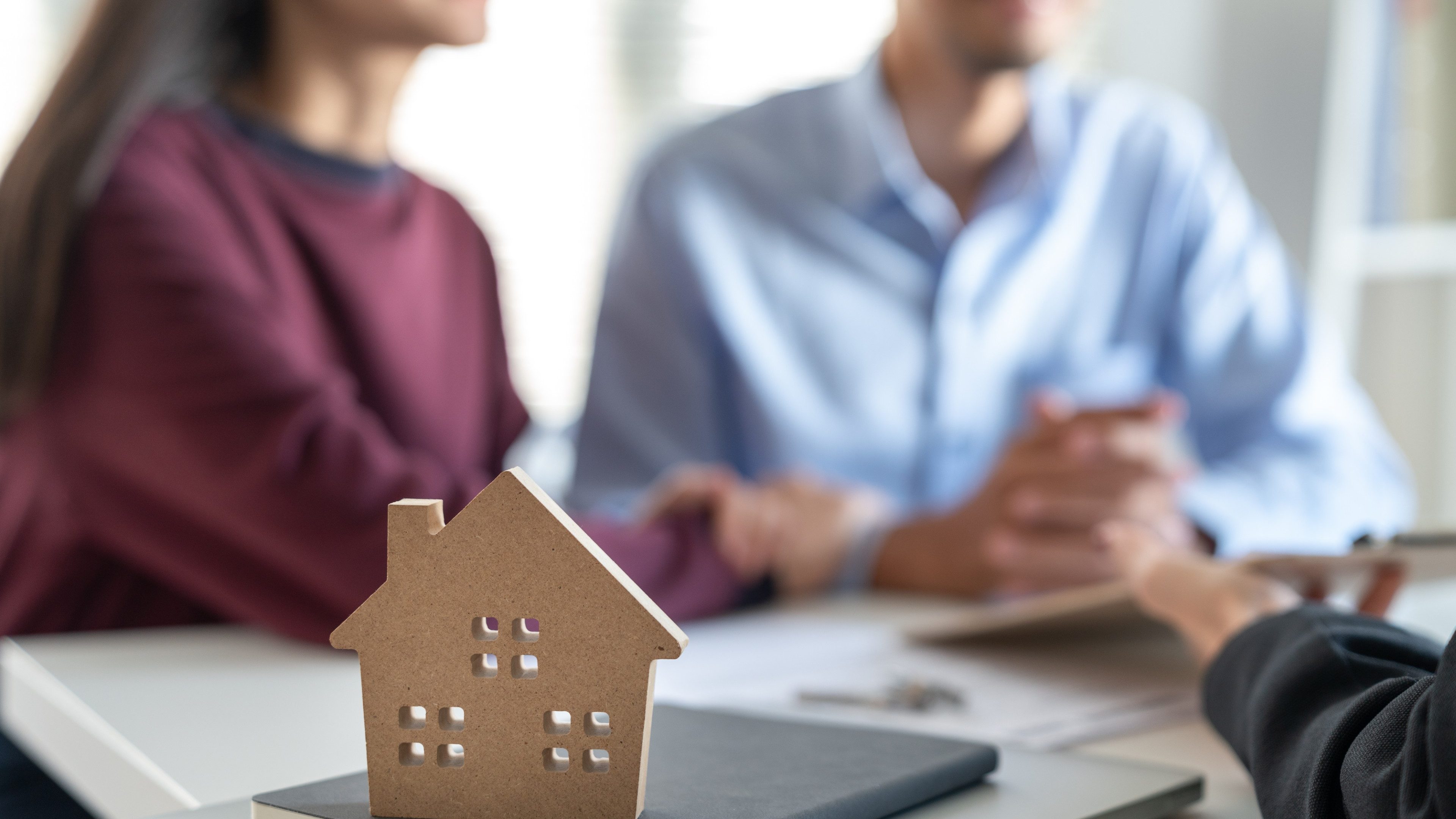 Young family couple talking with property real estate agent about home loan contract purchase agreement