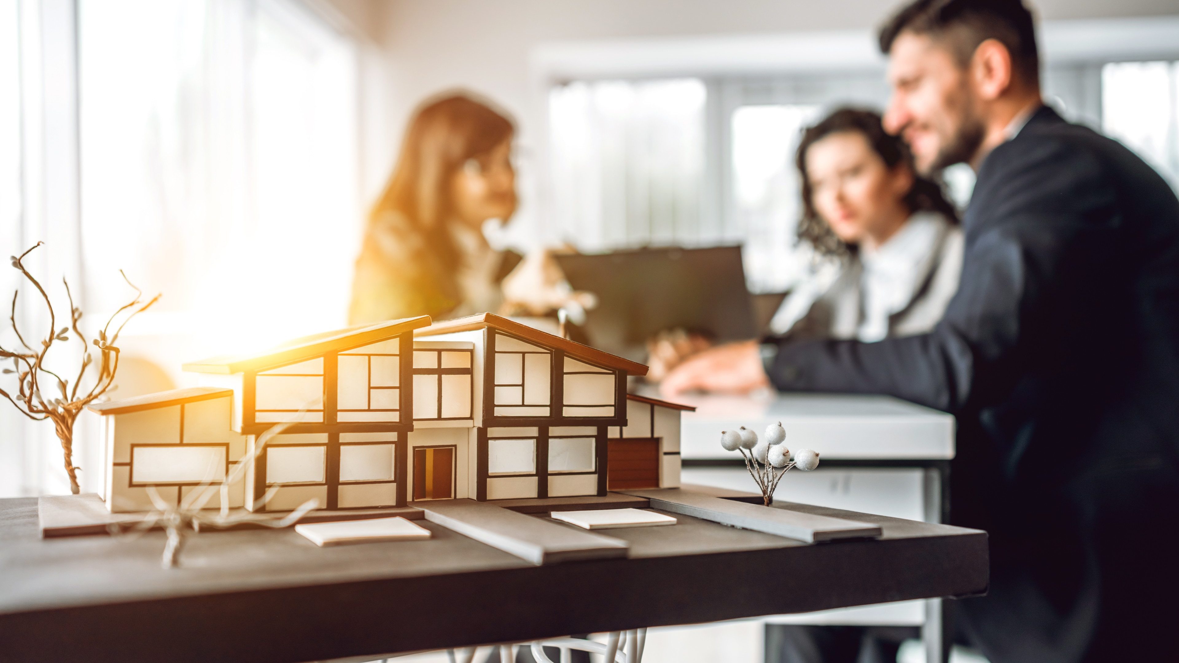 Close up image of house model with group business people on blurred background in building design studio. Architecture project concept