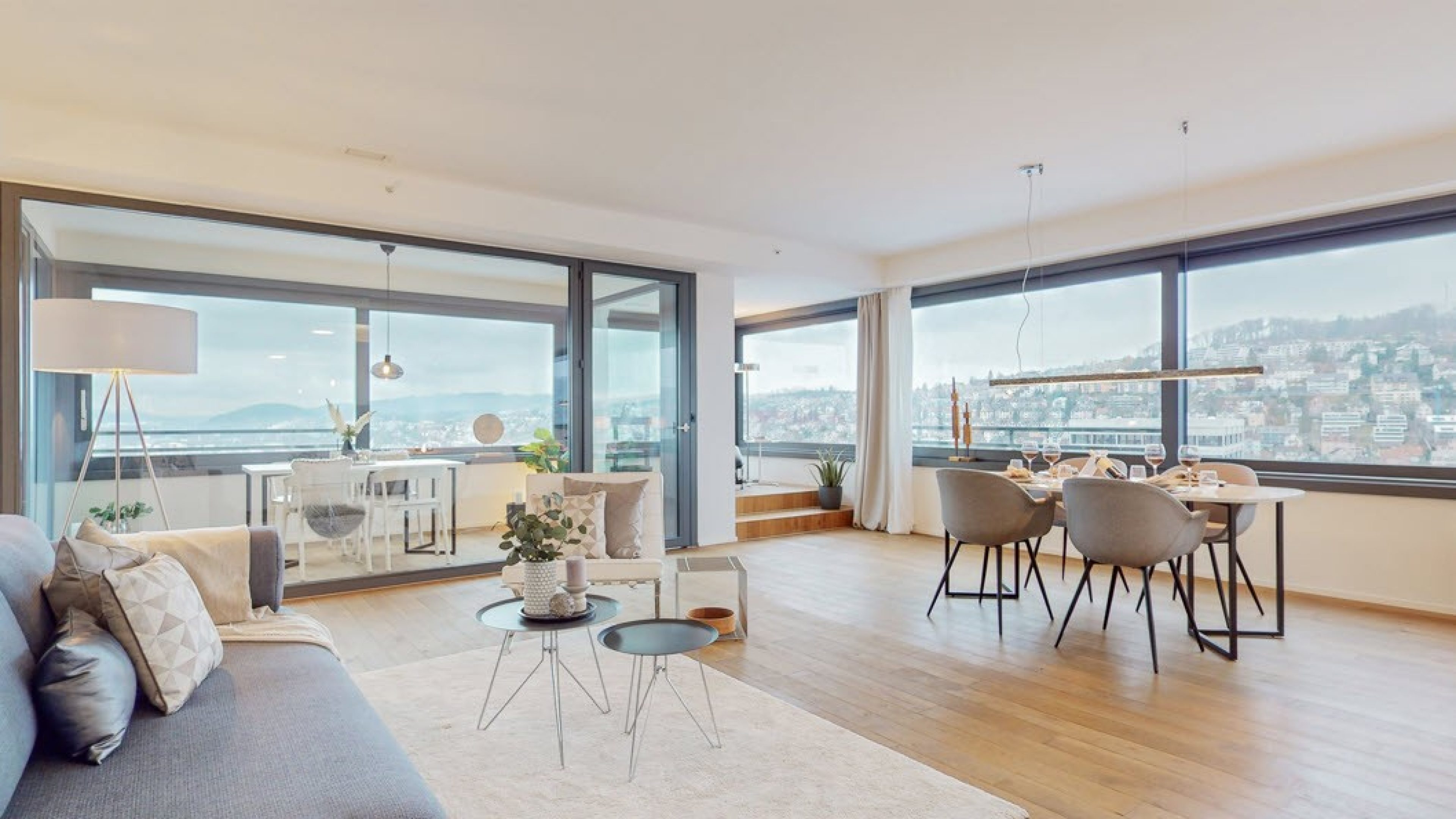 Séjour lumineux avec parquet, meublé avec canapé, table à manger et lampes. Grandes baies vitrées. 