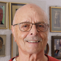 Das Portrait zeigt Meinrad Graf in Nahaufnahme vor einer Fotowand in seinem Zuhause. Er strahlt Stolz und Zufriedenheit aus, denn sein Zuhause ist eines seiner Lebenswerke.