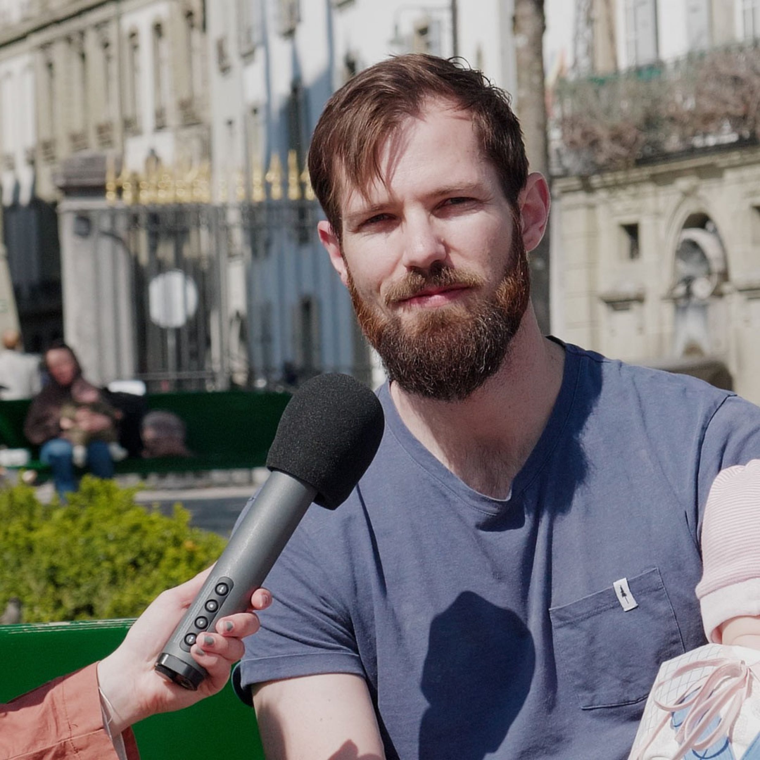 Mann in blauem T-Shirt spricht draussen ins Mikrofon