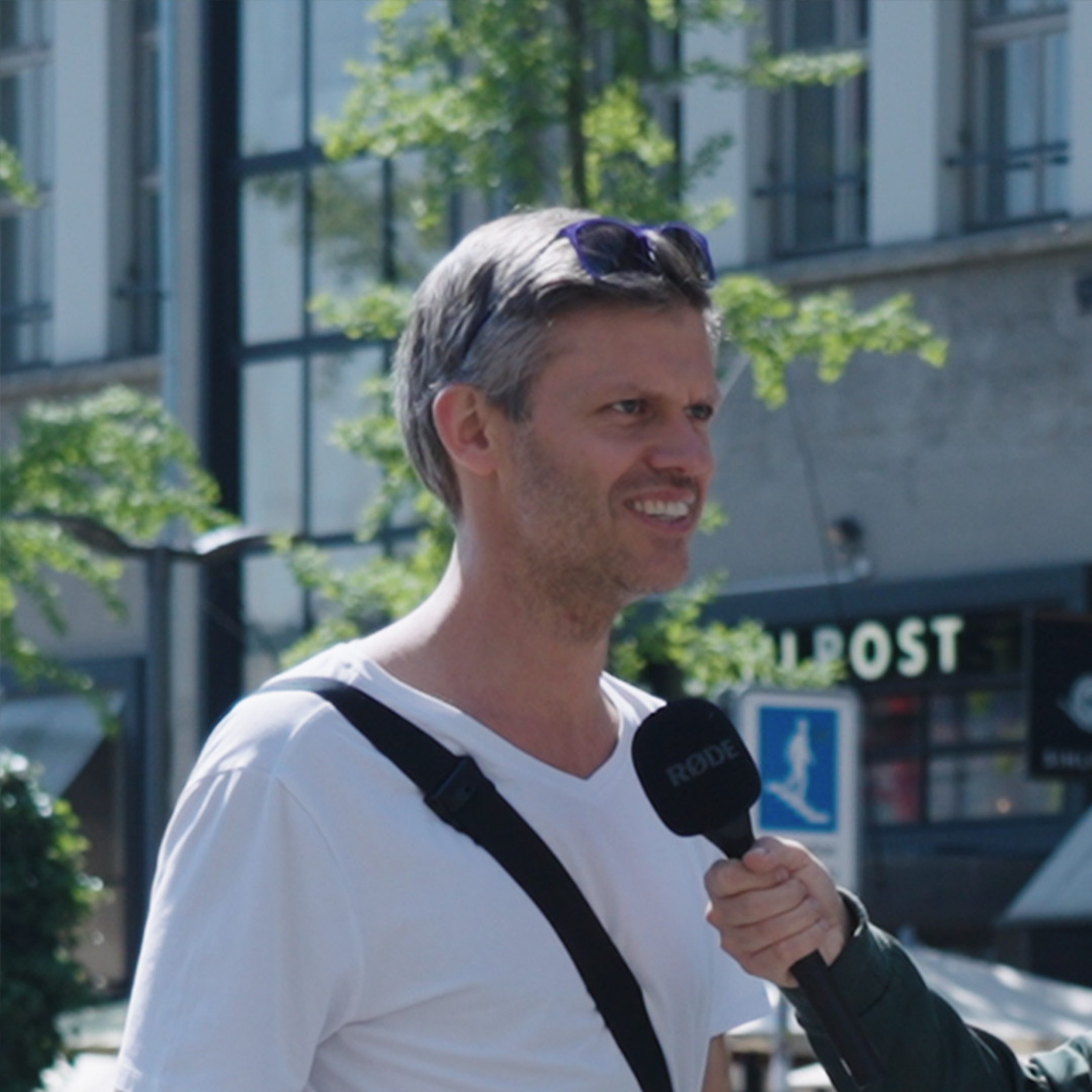 Photographie: Un homme debout à l’extérieur avec des lunettes de soleil sur la tête
