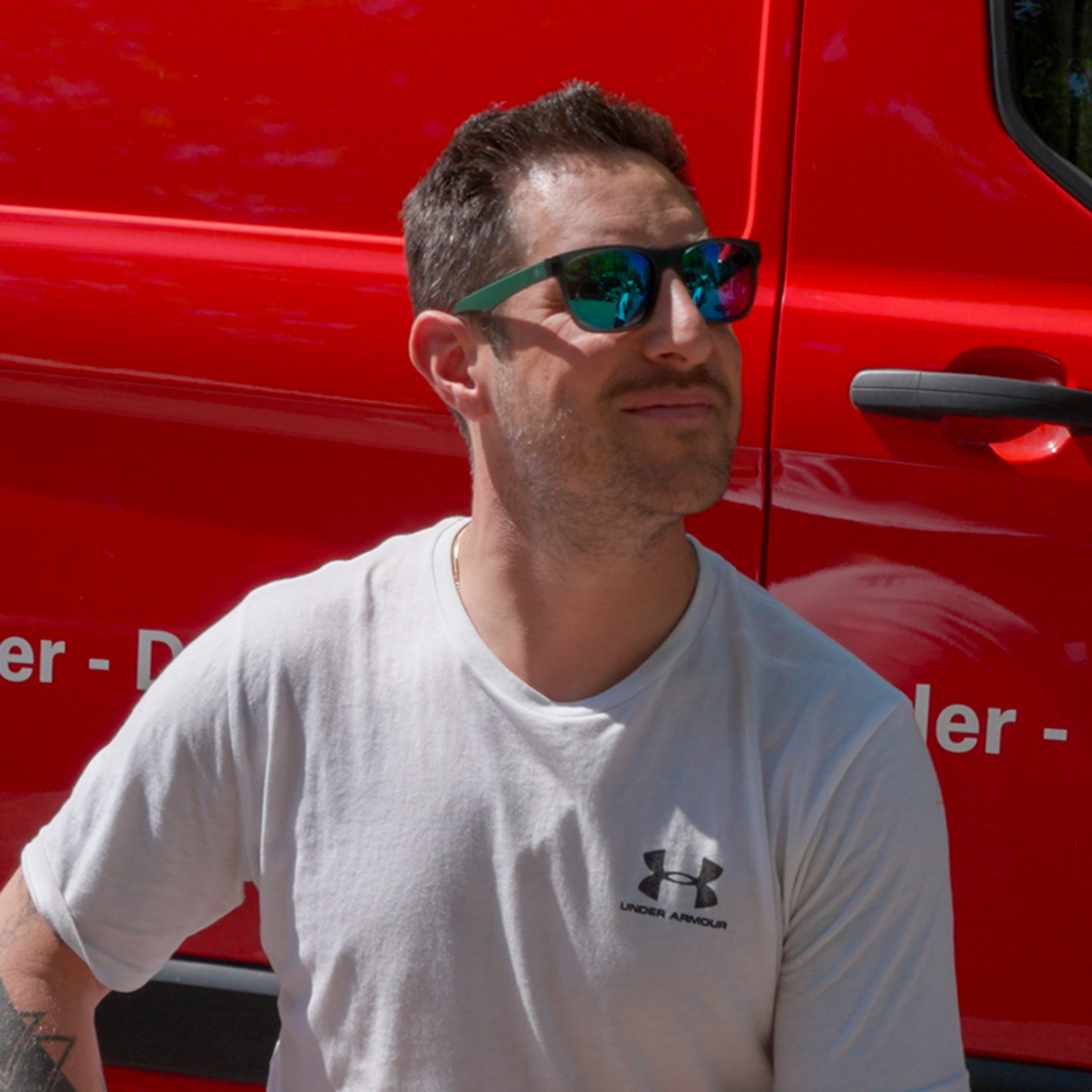 Portrait d’un homme devant une voiture rouge