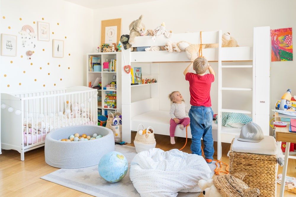 Une chambre d’enfant soigneusement meublée avec lit superposé et lit bébé.