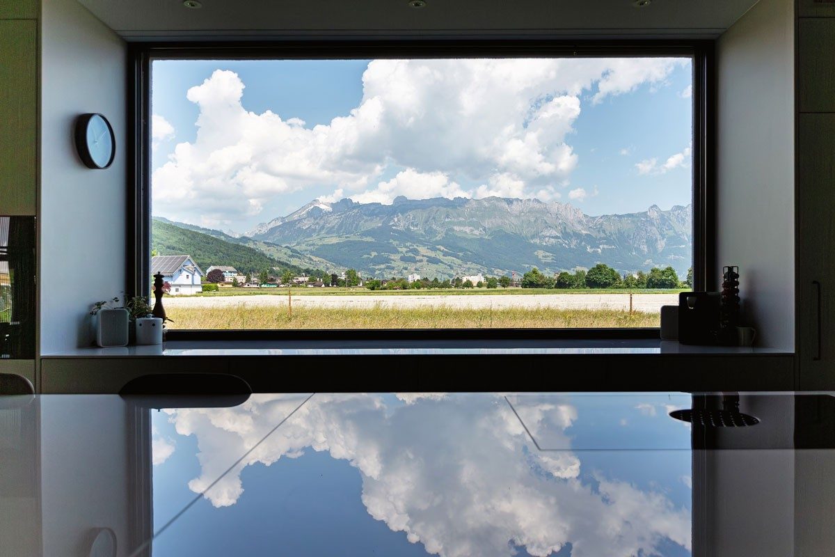 Une fenêtre dans une cuisine avec vue sur les montagnes.