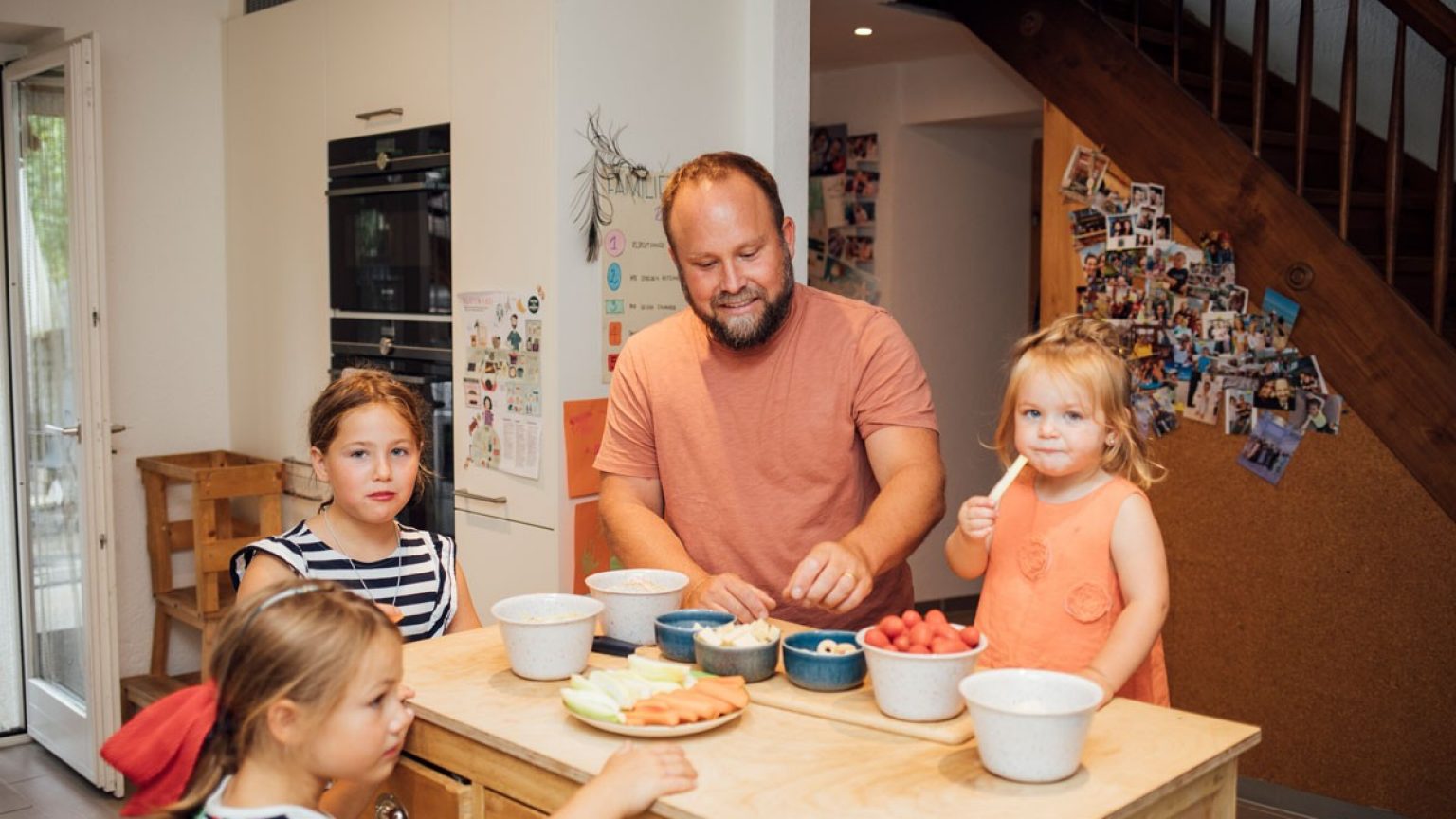 Le père prépare le repas avec trois enfants.