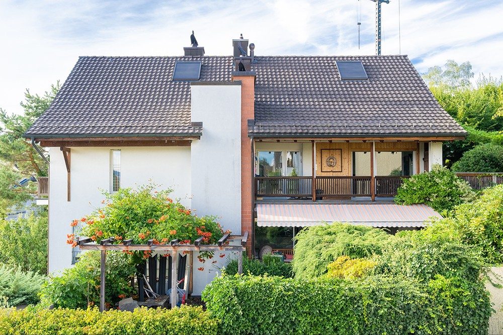 La maison est blanche avec quelques éléments en bois.