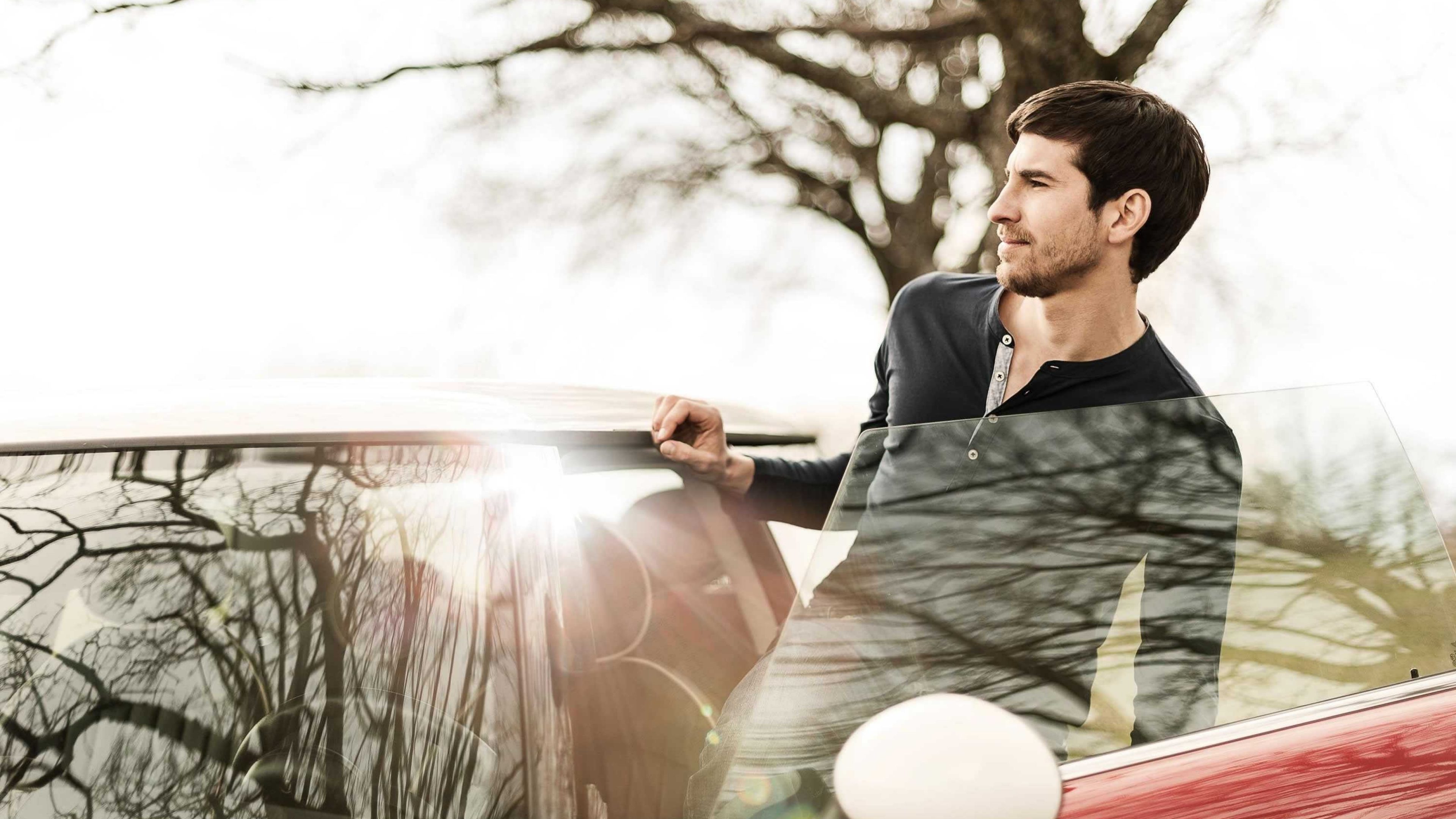 Un homme sort de sa voiture rouge.