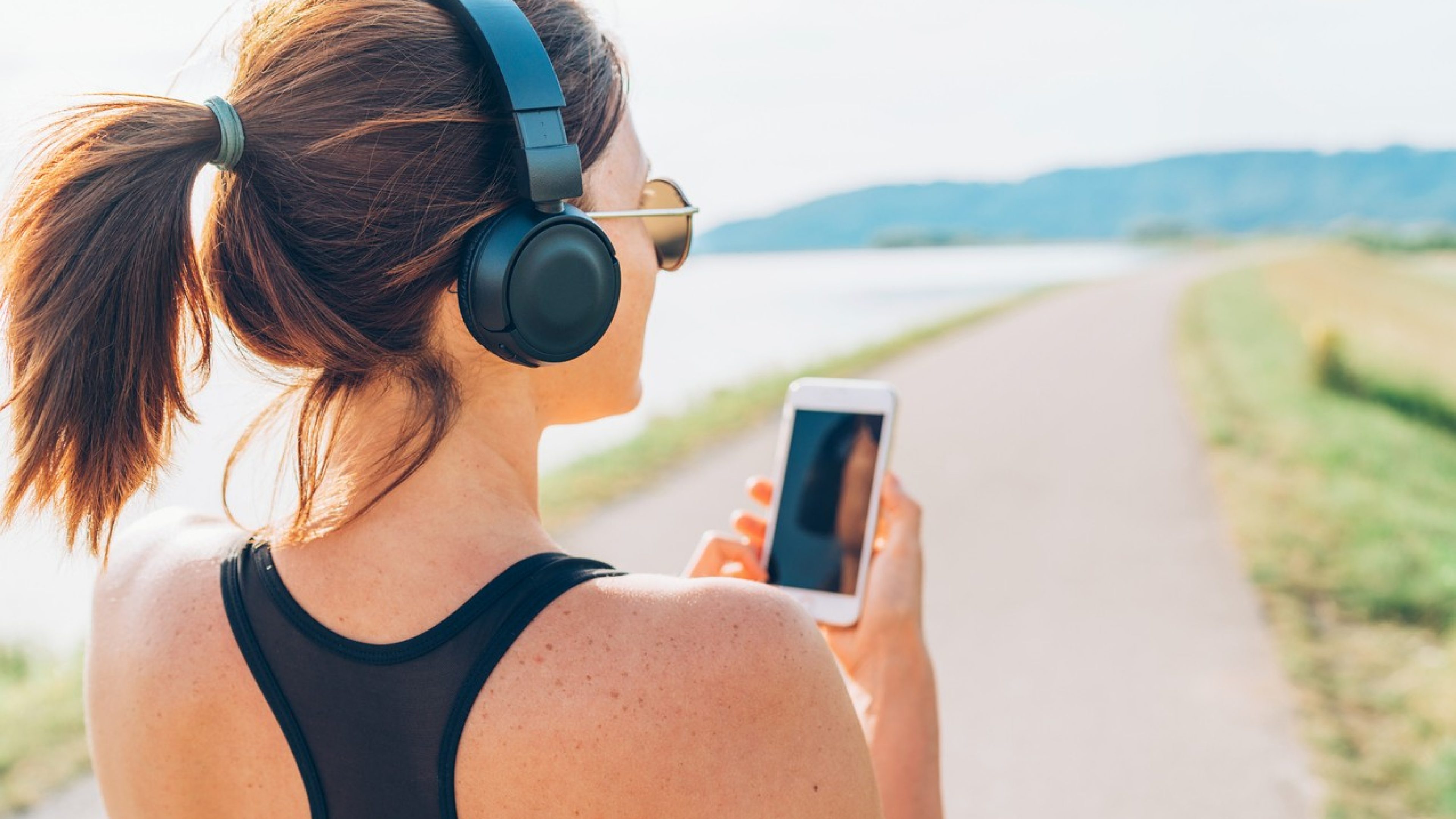 Young teenager girl starting jogging and listening to music using smartphone and wireless headphones. Active sport life concept image.