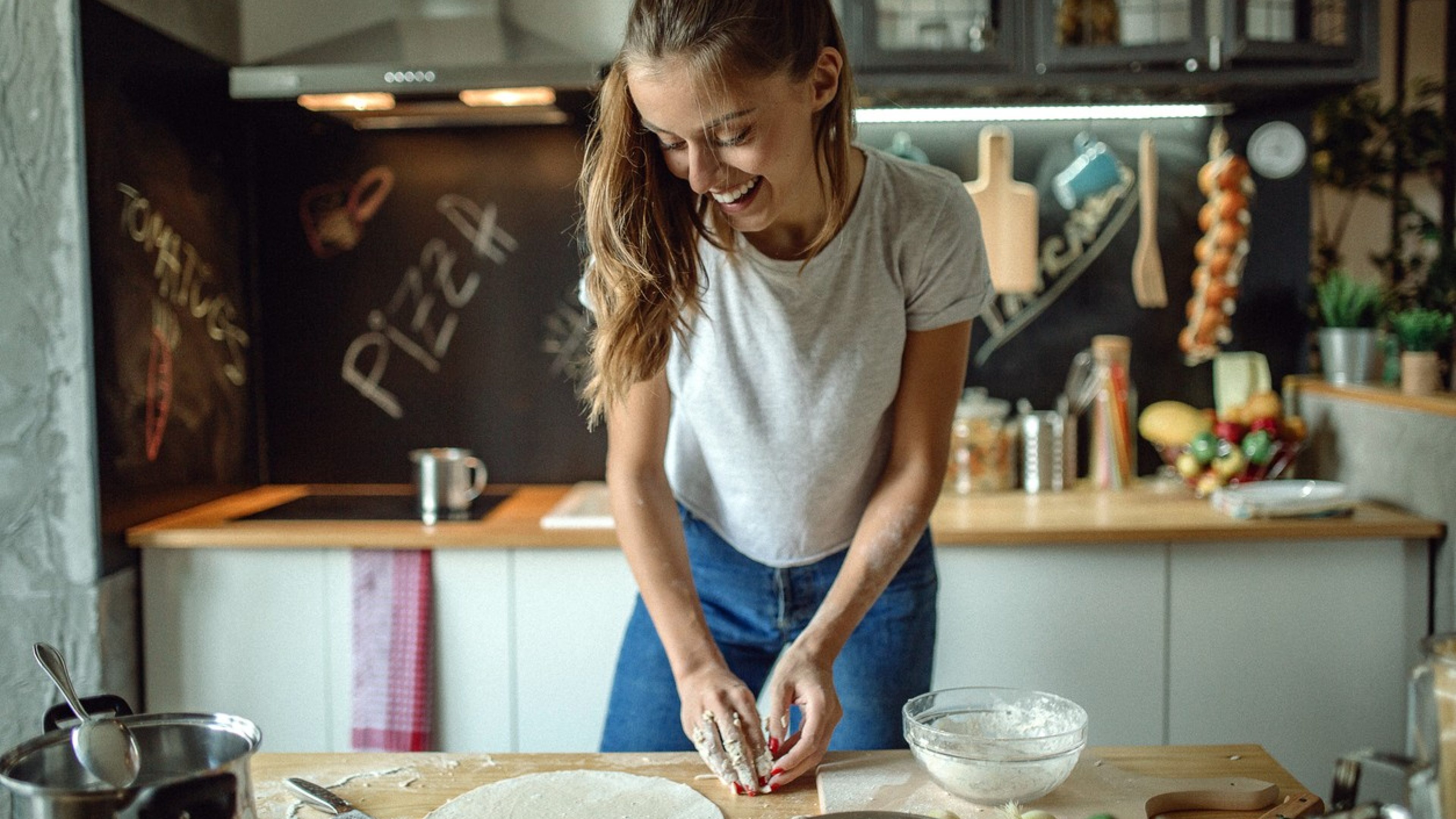 Woman in kitchen preparing dough for pizza