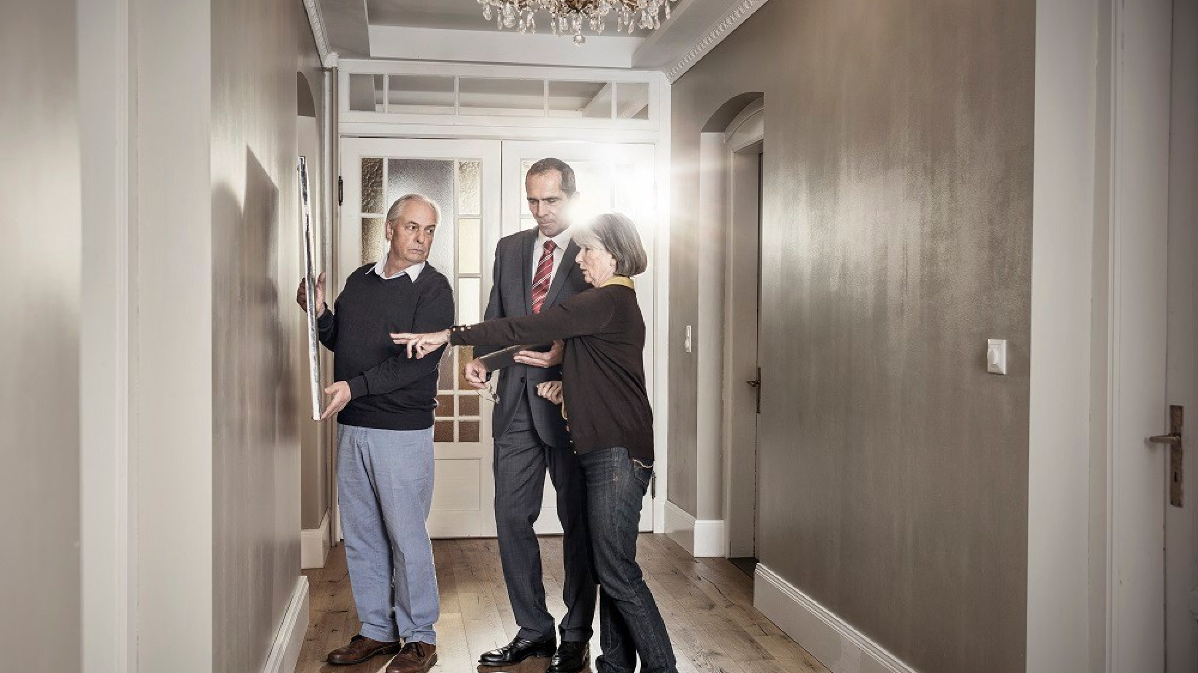 Un couple âgé montre à un conseiller une photo dans son logement en propriété.