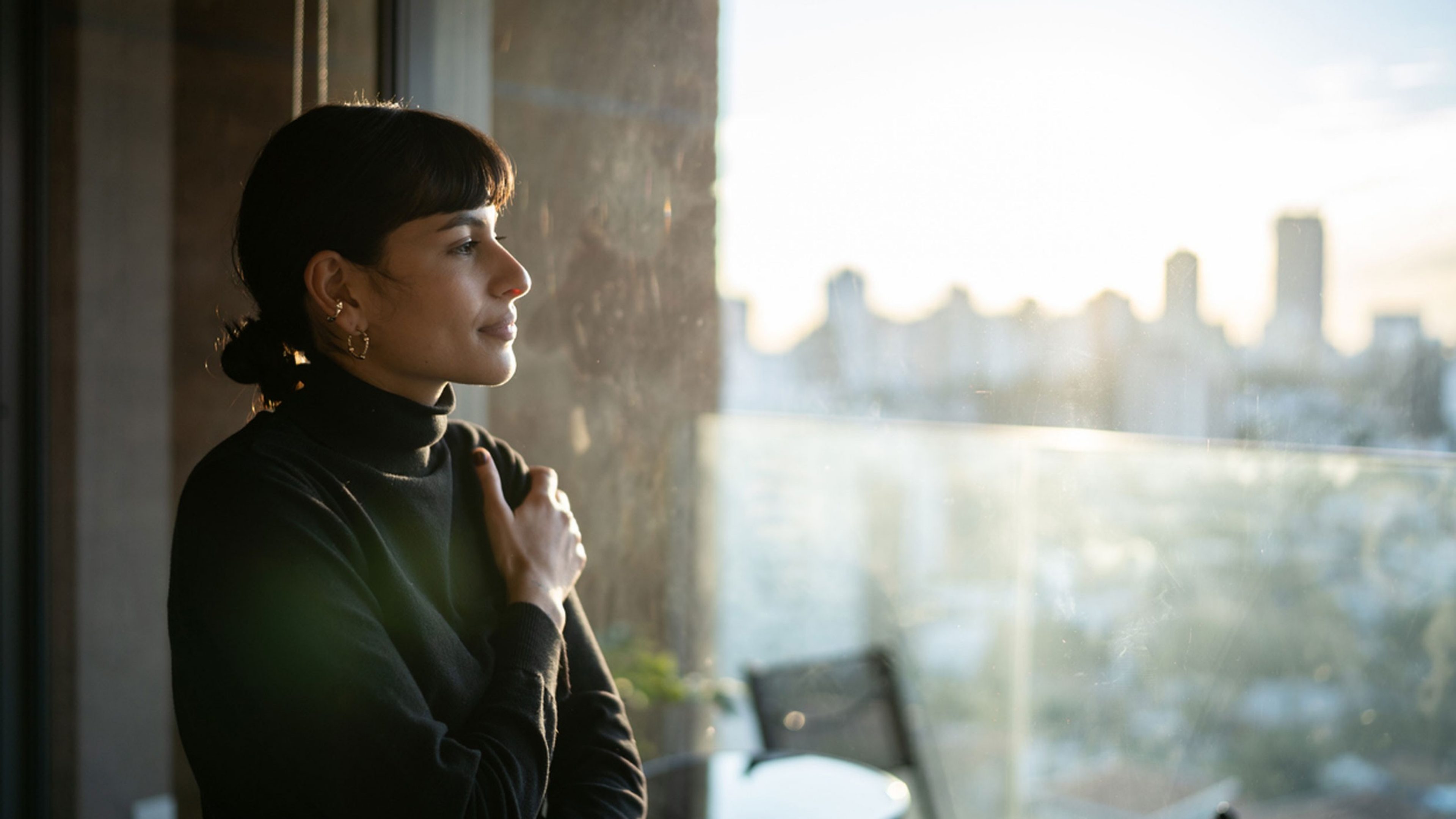 Une femme se tient à une fenêtre et pense