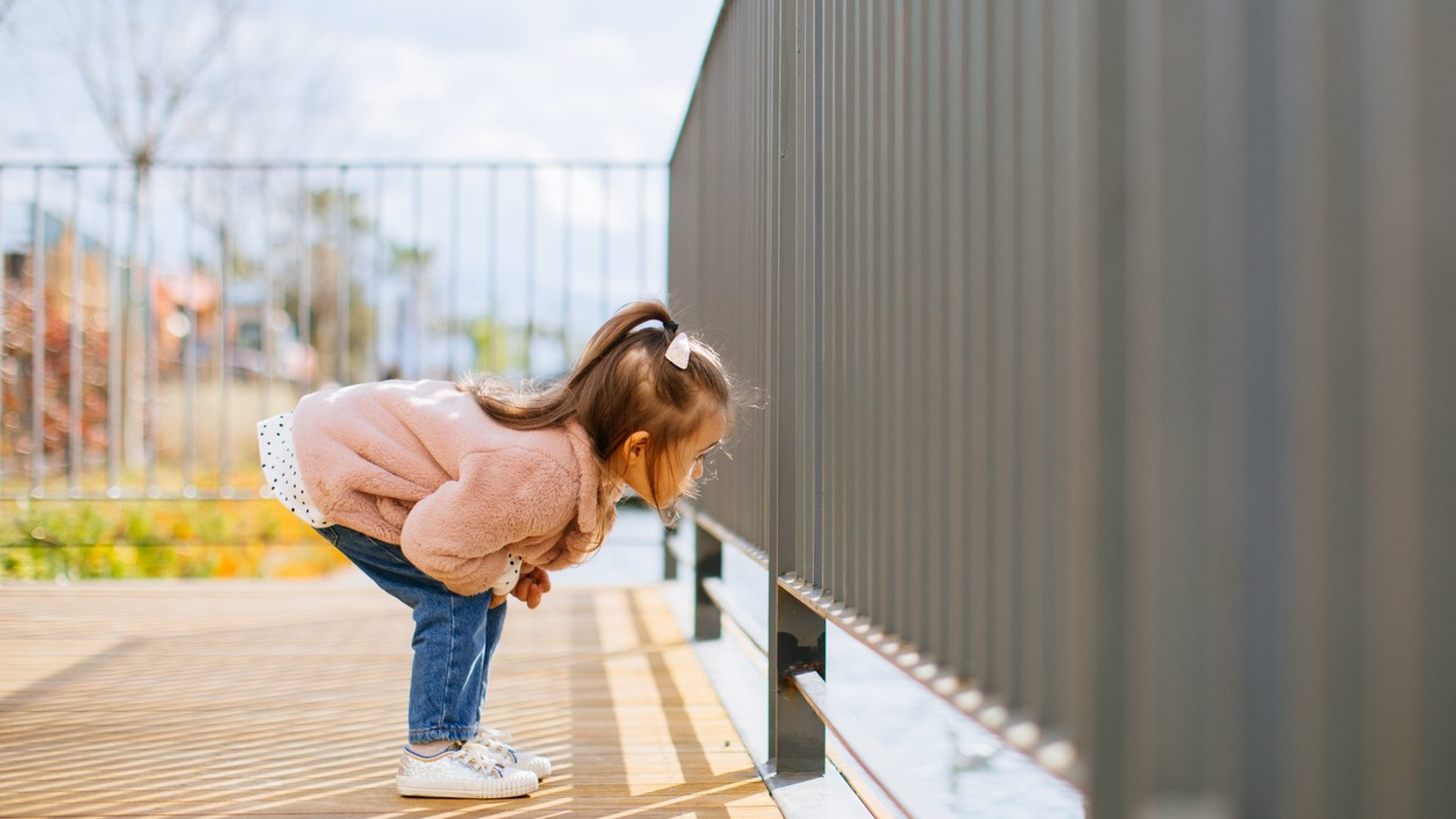 Une petite fille à la recherche d’œufs de Pâques se penche près d’une balustrade.