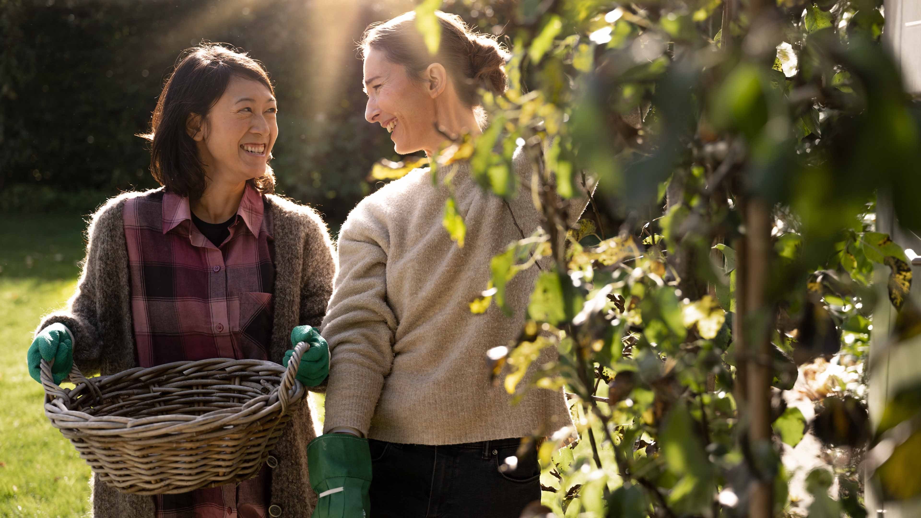 Deux femmes cueillent leur récolte dans un jardin.