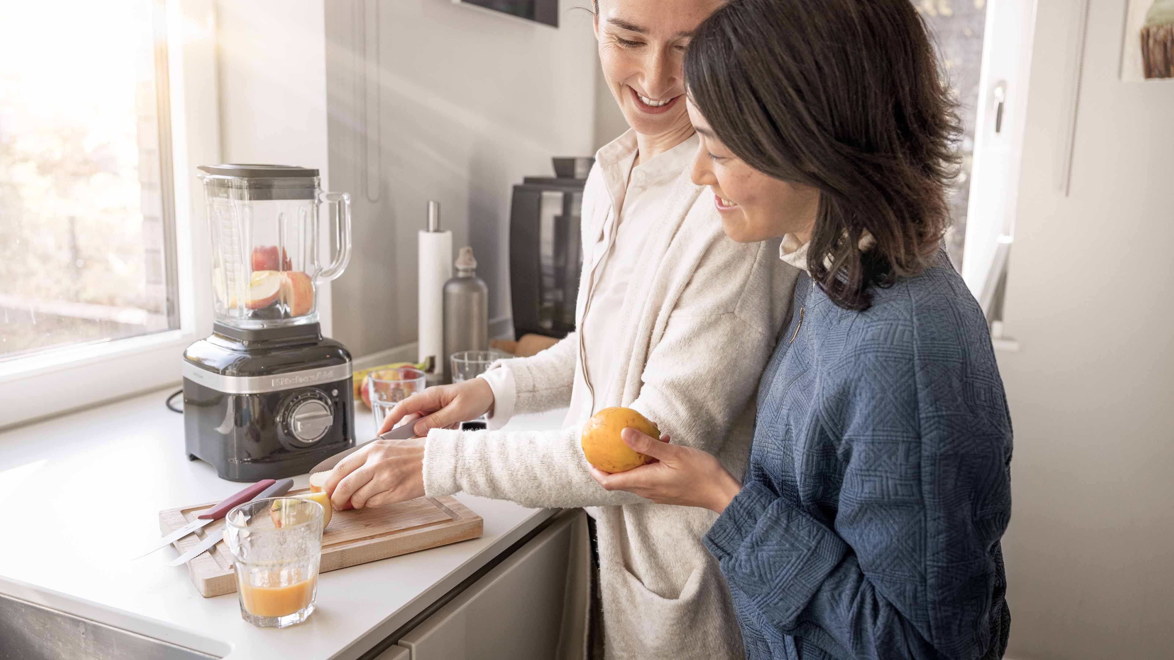 Deux femmes pressent du jus d’orange frais dans la cuisine.