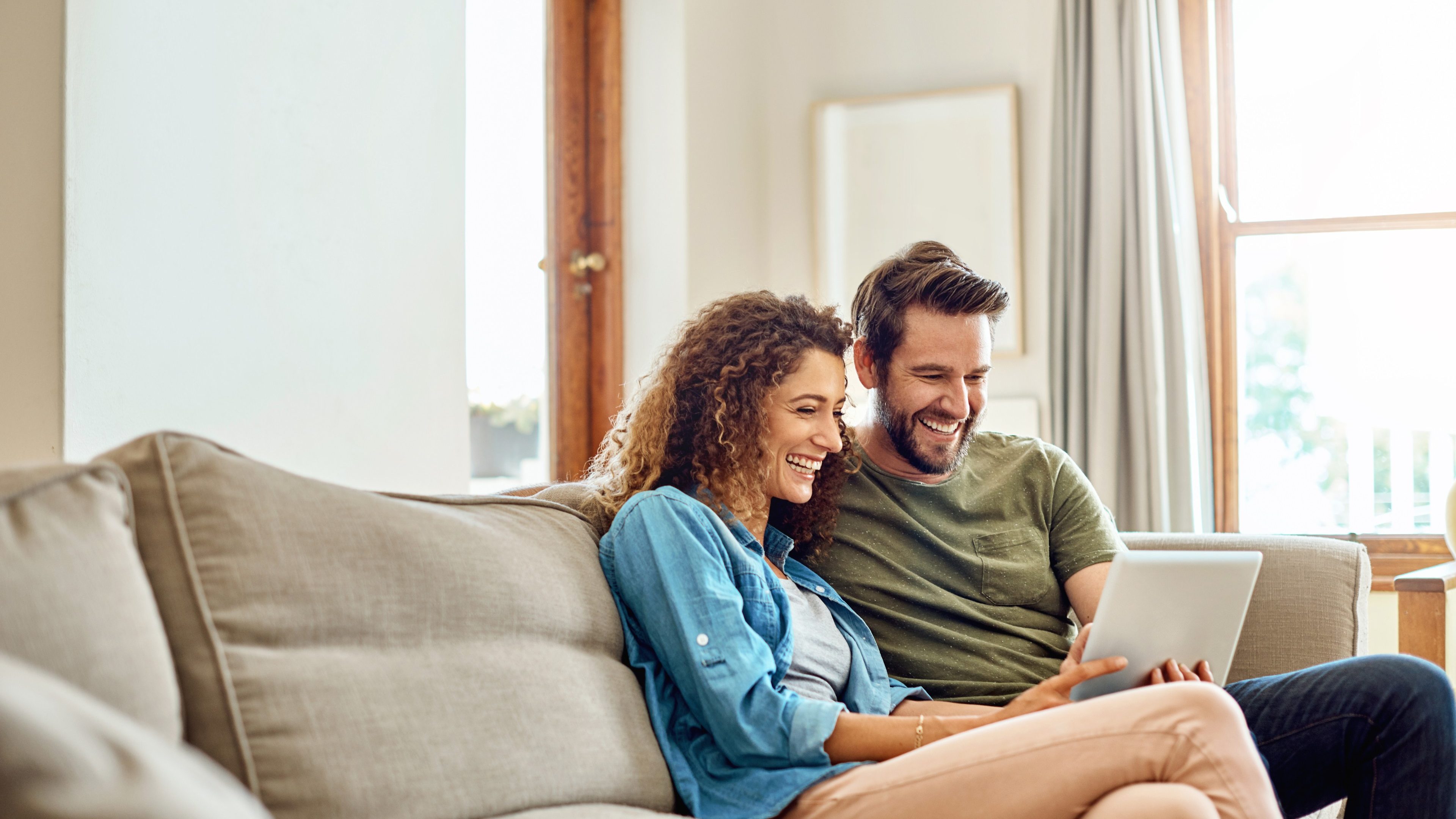 Shot of a happy young couple using a digital tablet together on the sofa at home