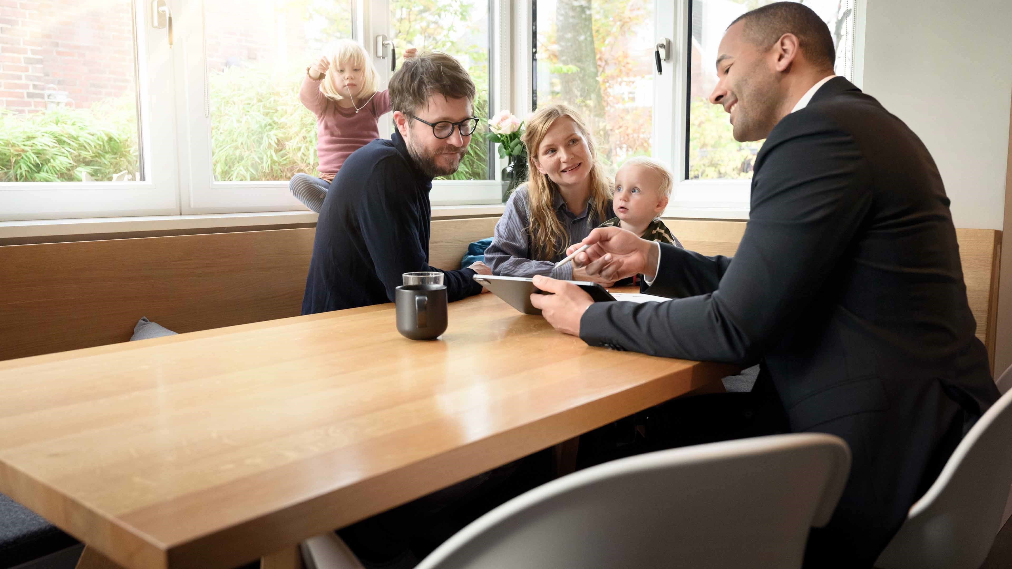 Un conseiller en prévoyance avec un couple deux enfants à la table de la cuisine