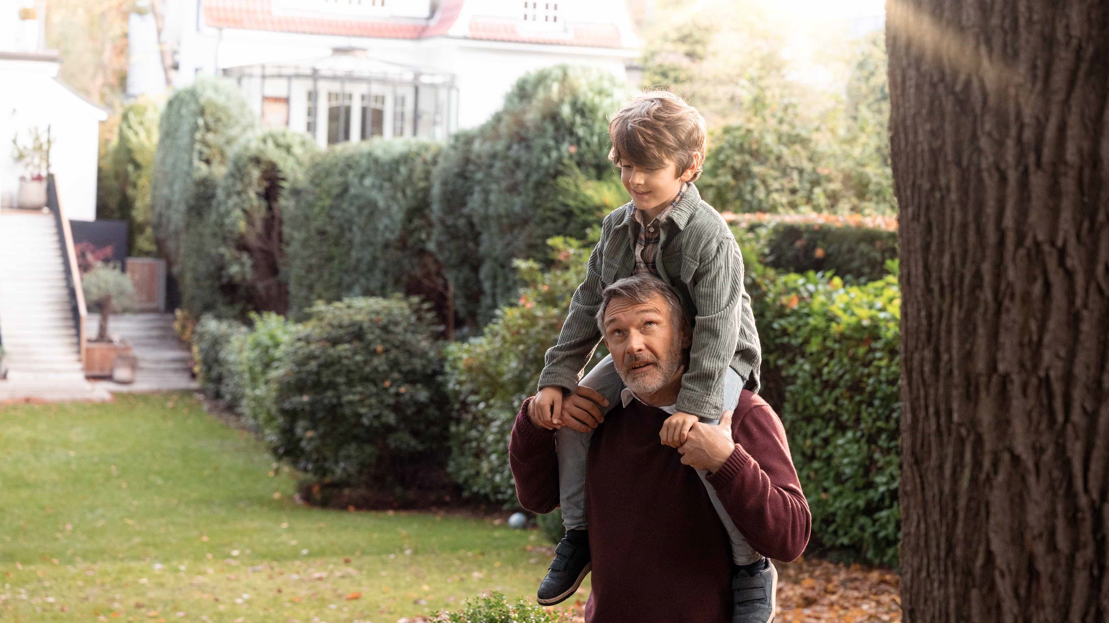 Un grand-père avec son petit-fils sur les épaules dans le jardin