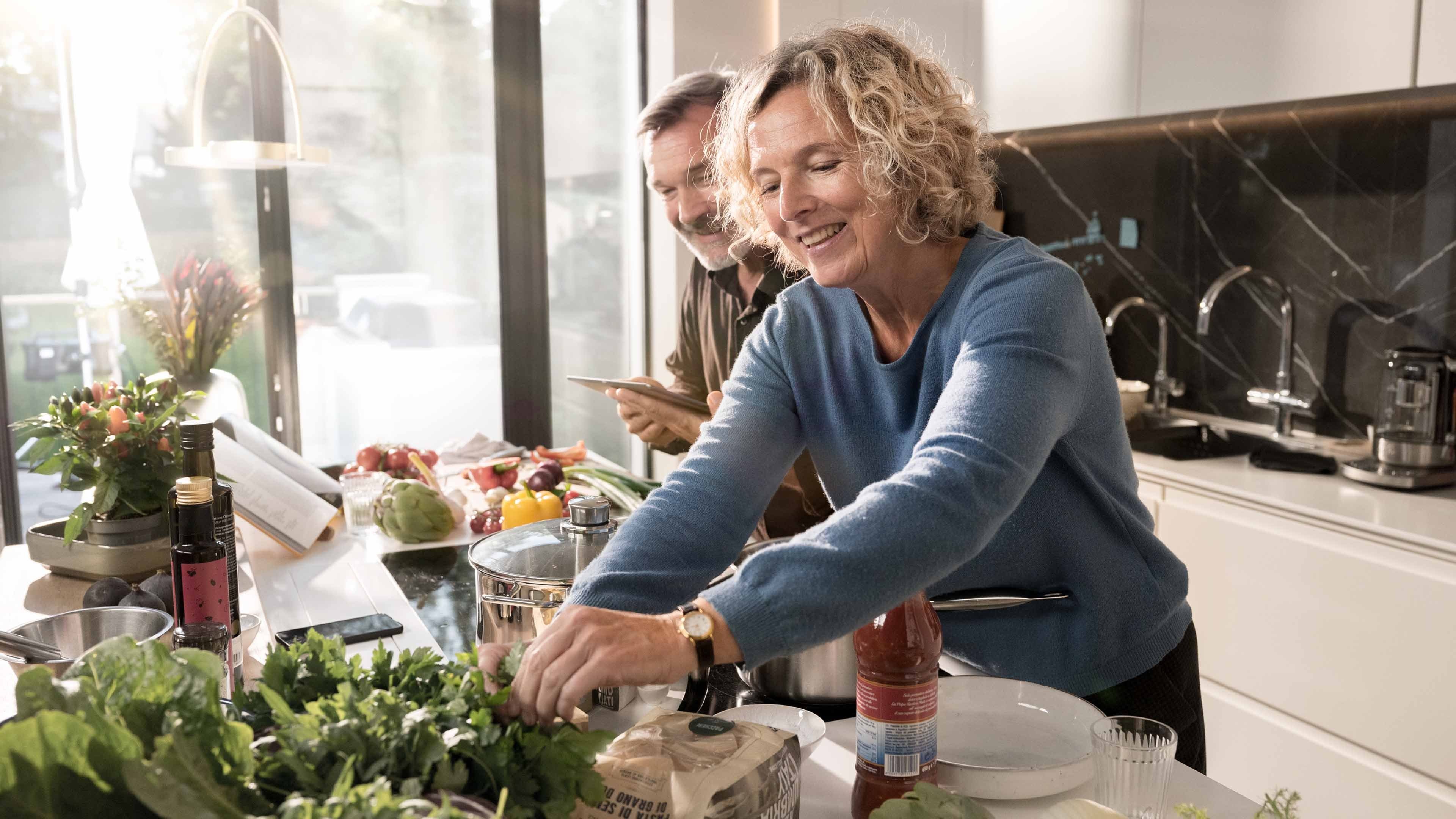 Une femme et un homme cuisinent un plat italien.