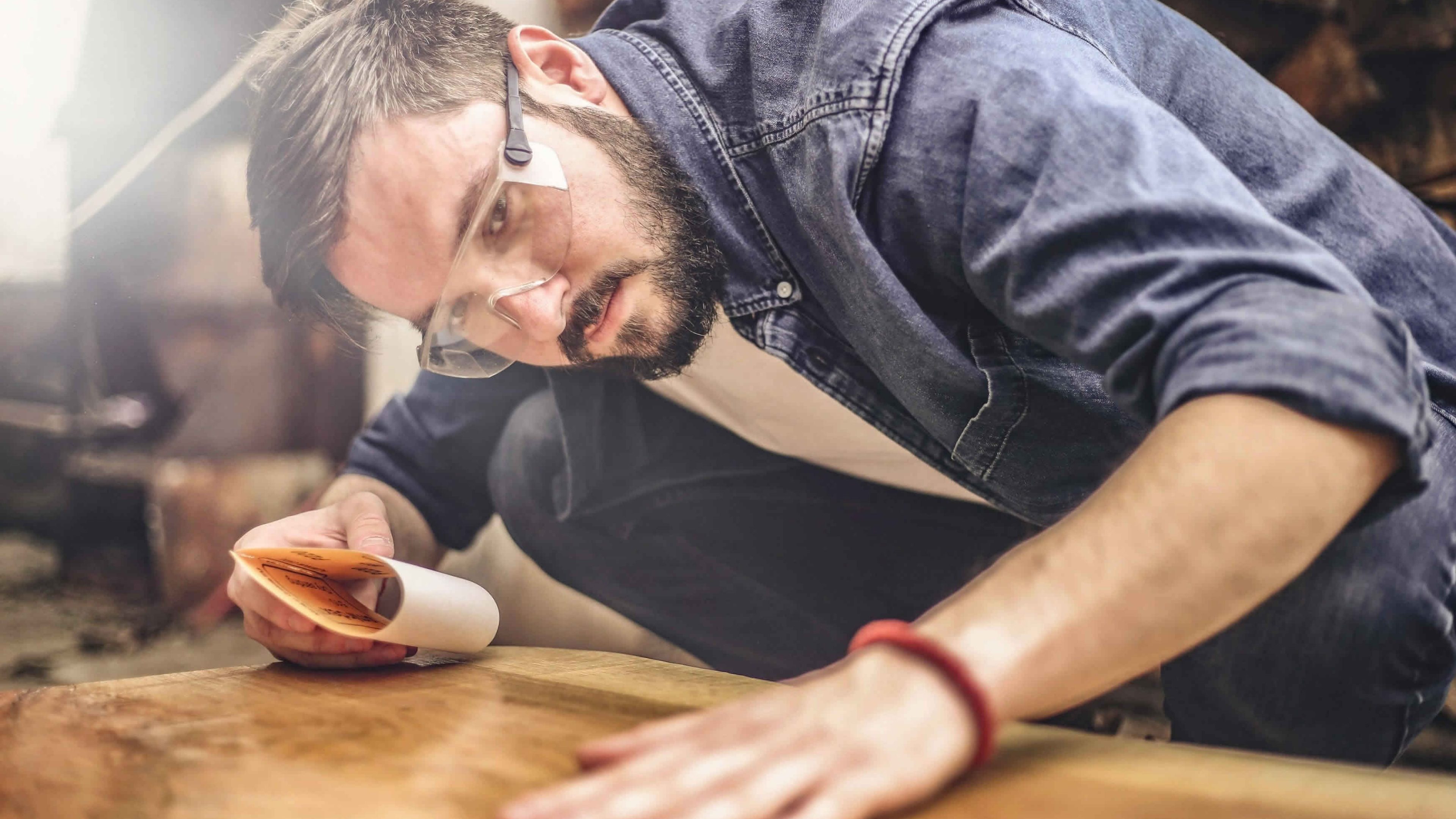 Un jeune homme travaille sur une surface en bois.