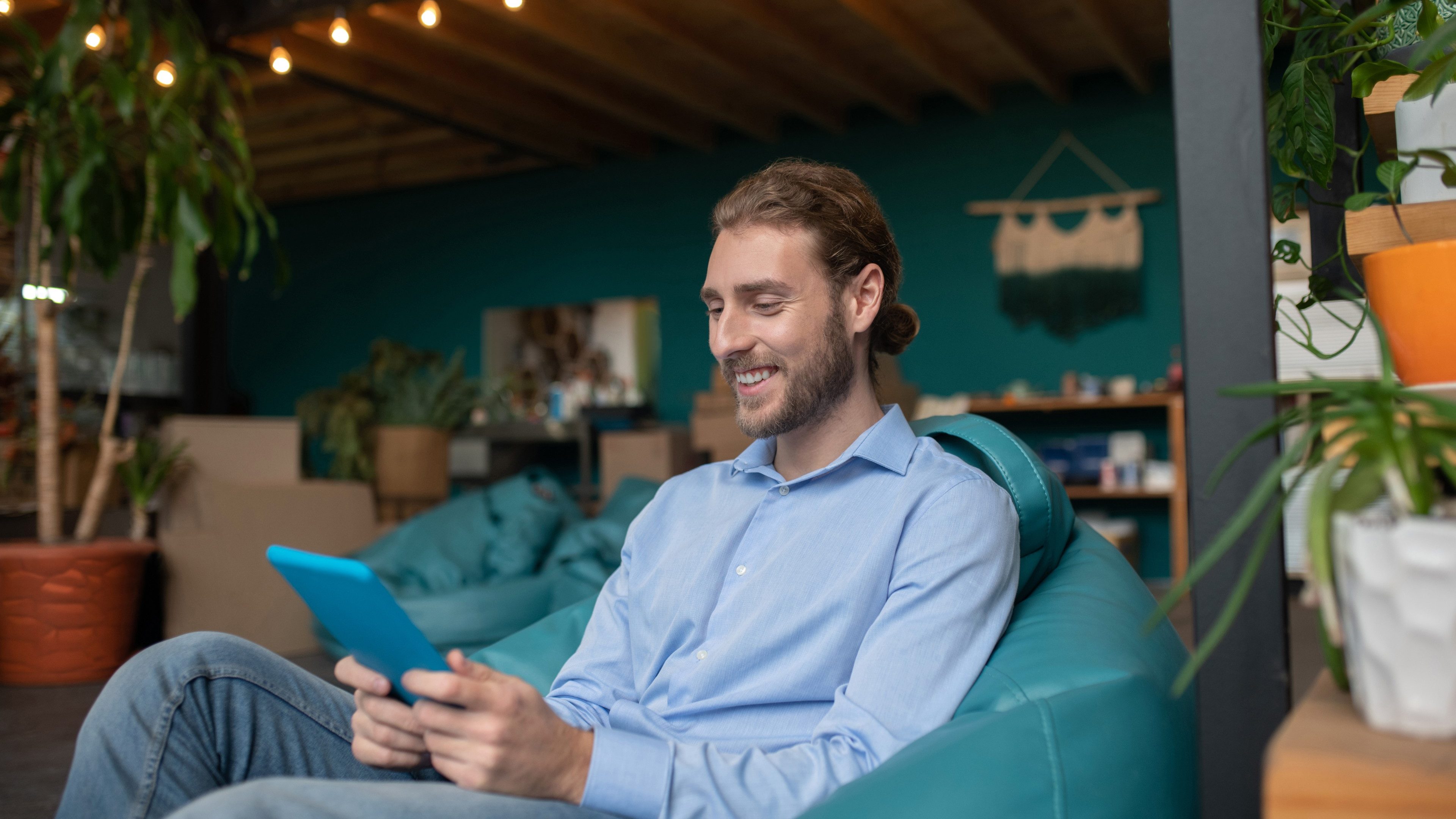 Having a break. A smiling man sitting in armchair and using a tablet
