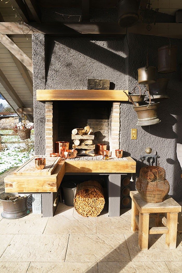 Un camino con decorazioni in legno su una terrazza soleggiata.