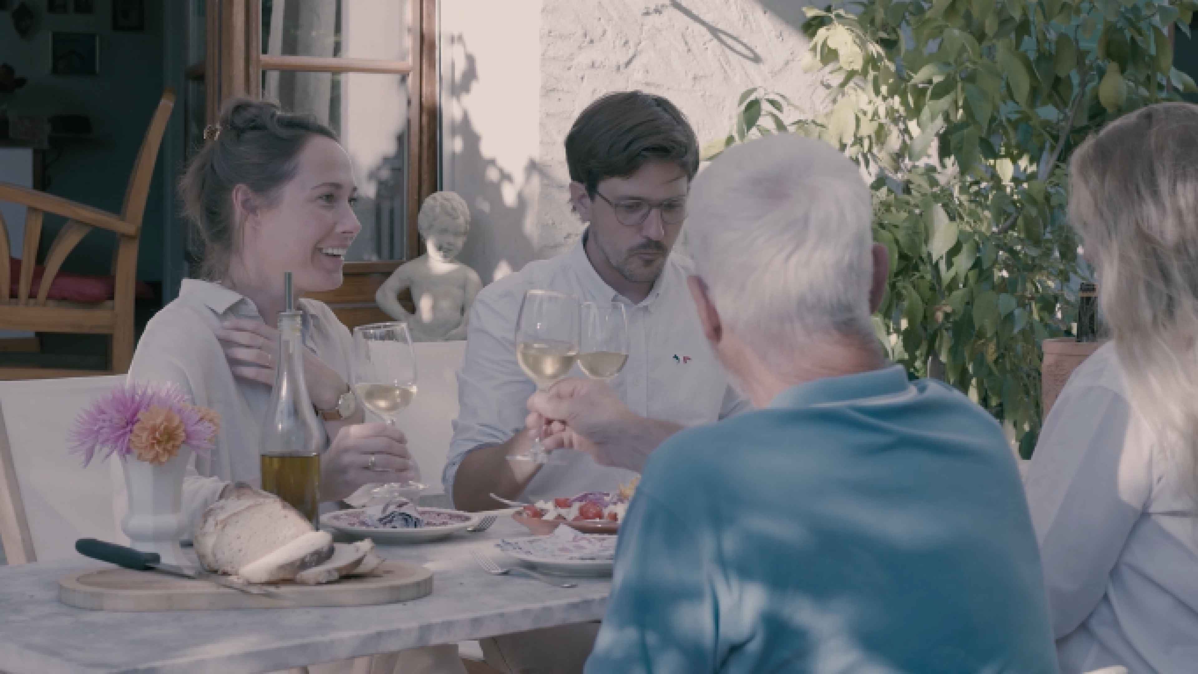 Quattro persone brindano con un bicchiere di vino in terrazza. 