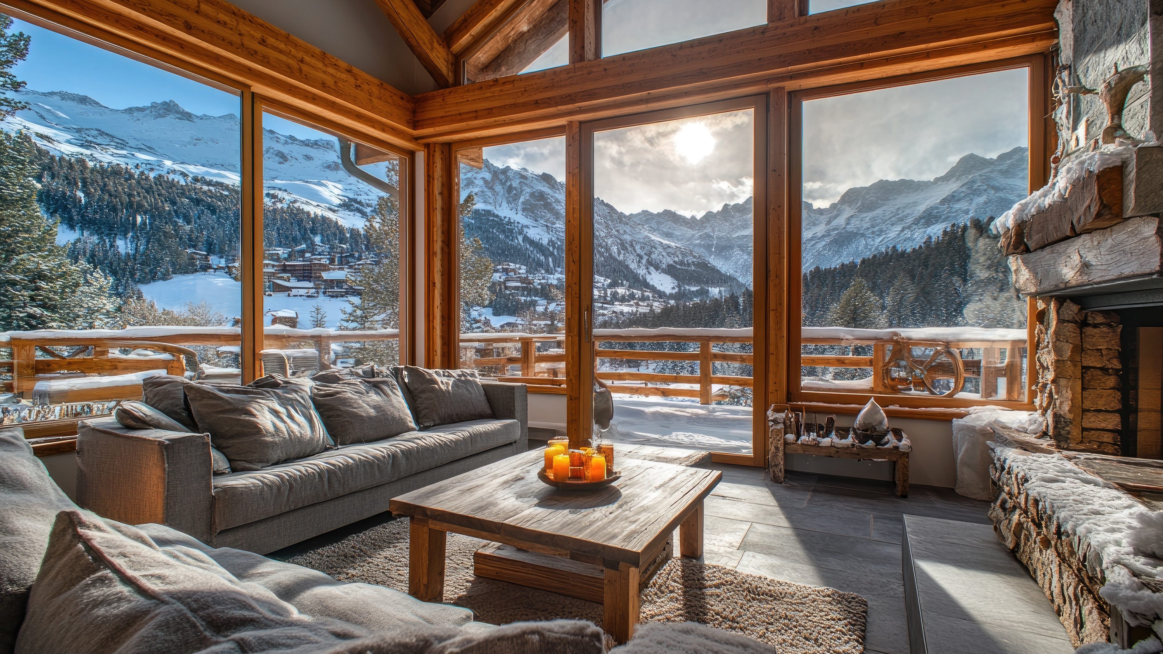 Modern chalet interior with a burning fireplace and large windows overlooking a snowy mountain range