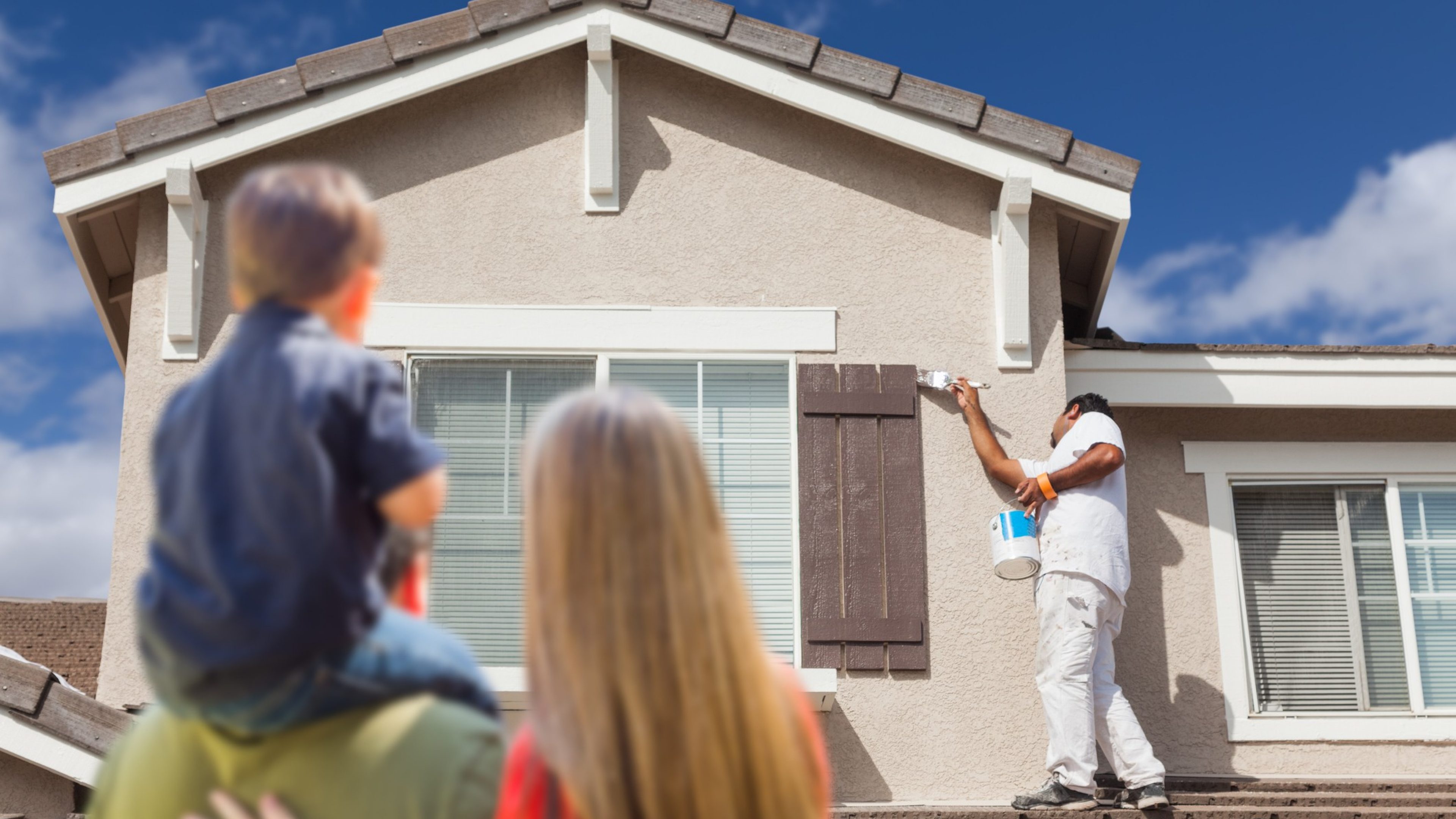 Young Family Watching Home Get Painted by House Painter.