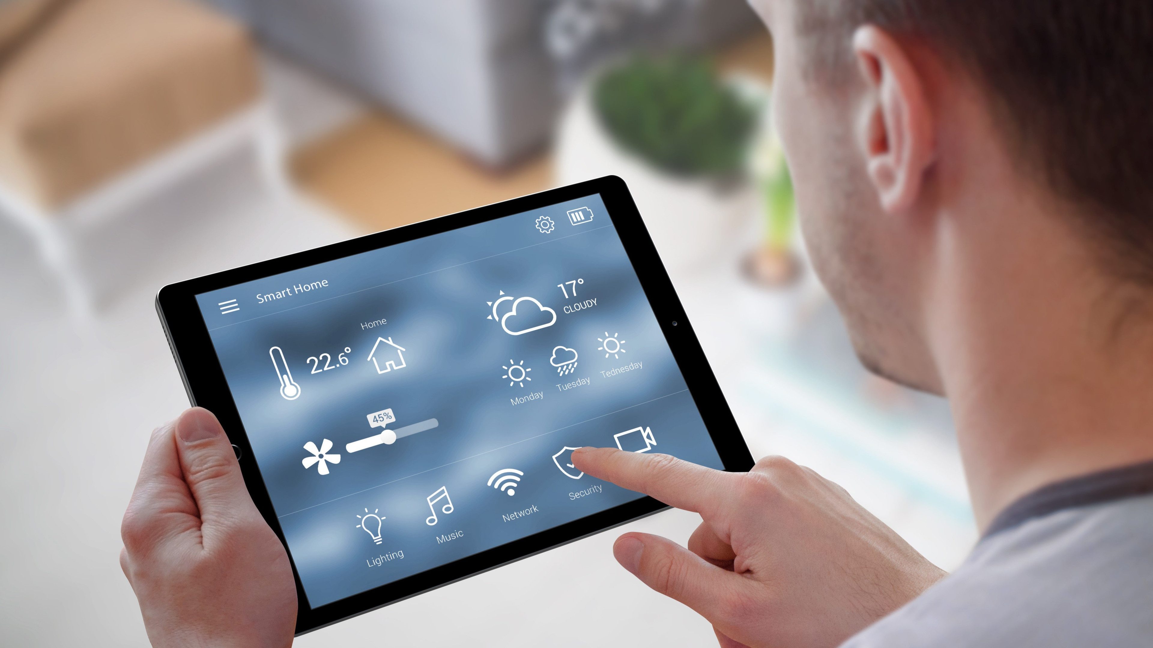 Un uomo tiene in mano un iPad e controlla le app per la casa intelligente.