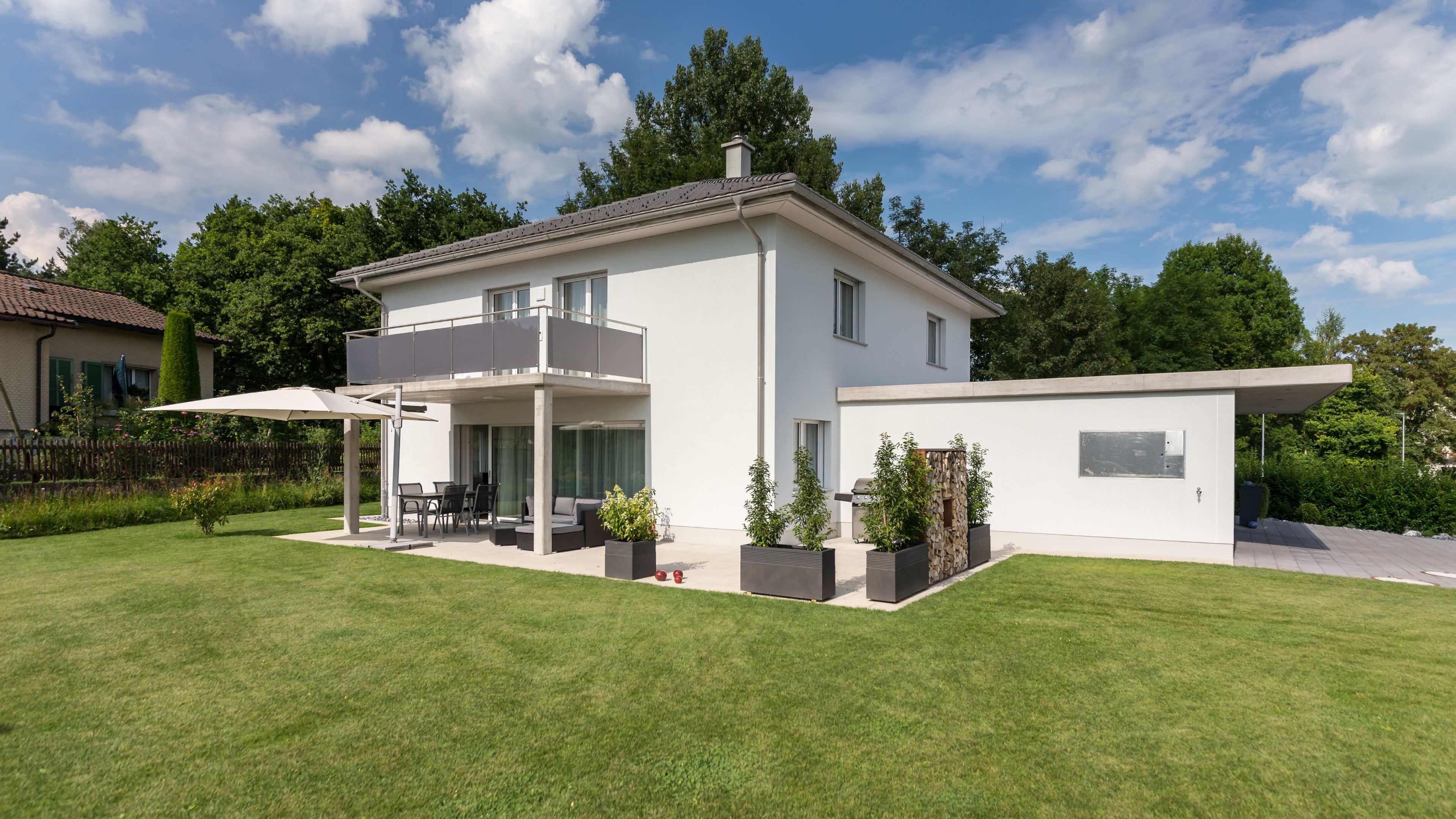 Casa unifamiliare semplice e moderna con balcone, dehors e prato curato senza piante.