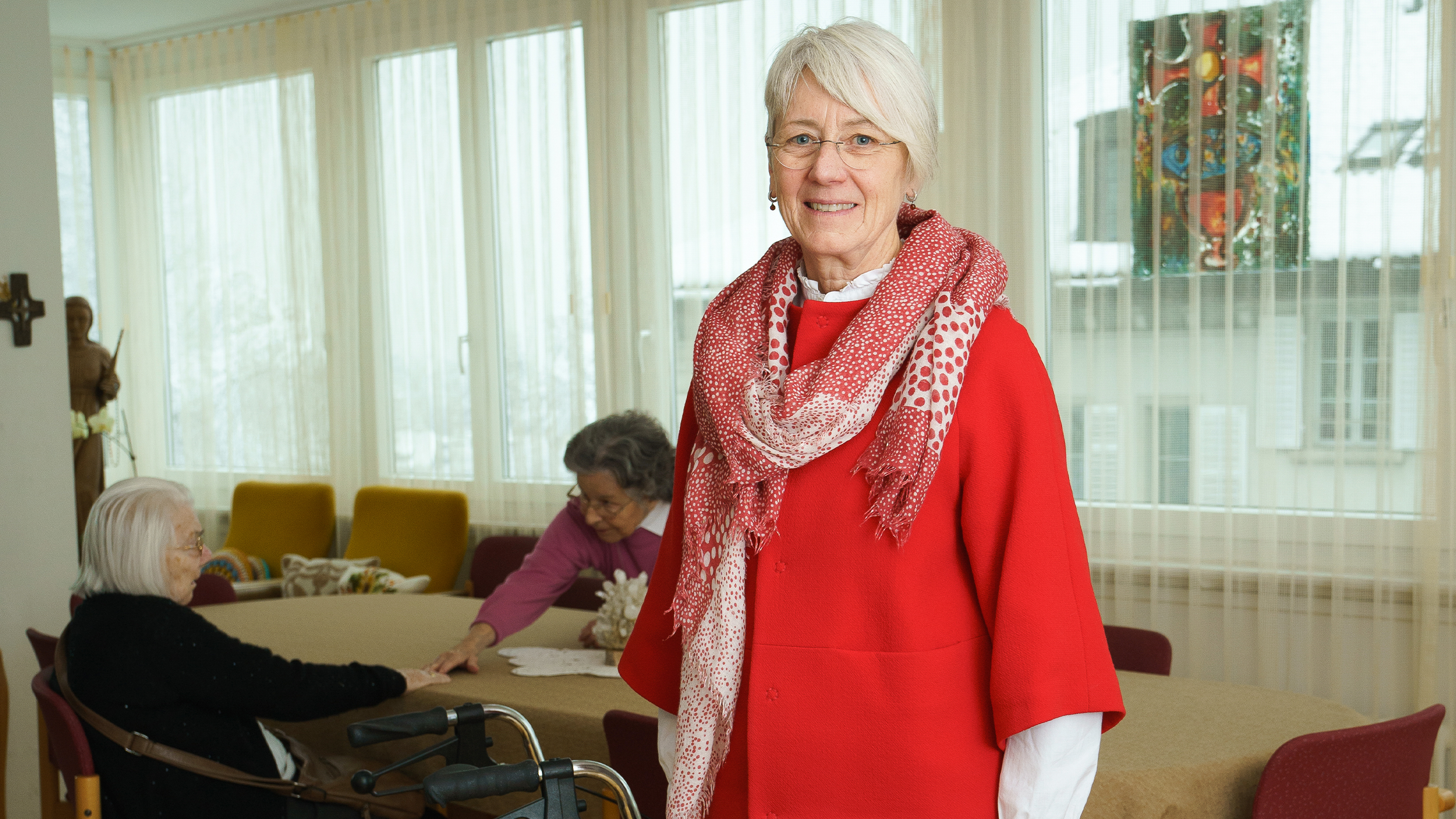 Hedy Gadient, Leiterin eines Seniorenwohnheims, steht stolz im Gemeinschaftsraum ihrer Einrichtung. Mit ihrem Engagement und ihrer Fürsorge schafft sie einen Ort des Wohlbefindens für ihre Bewohner.
