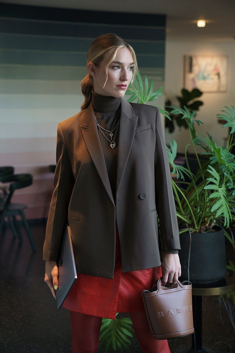 Manuela Frey, vestita in giacca marrone e maglione a girocollo, guarda fuori dalla finestra.