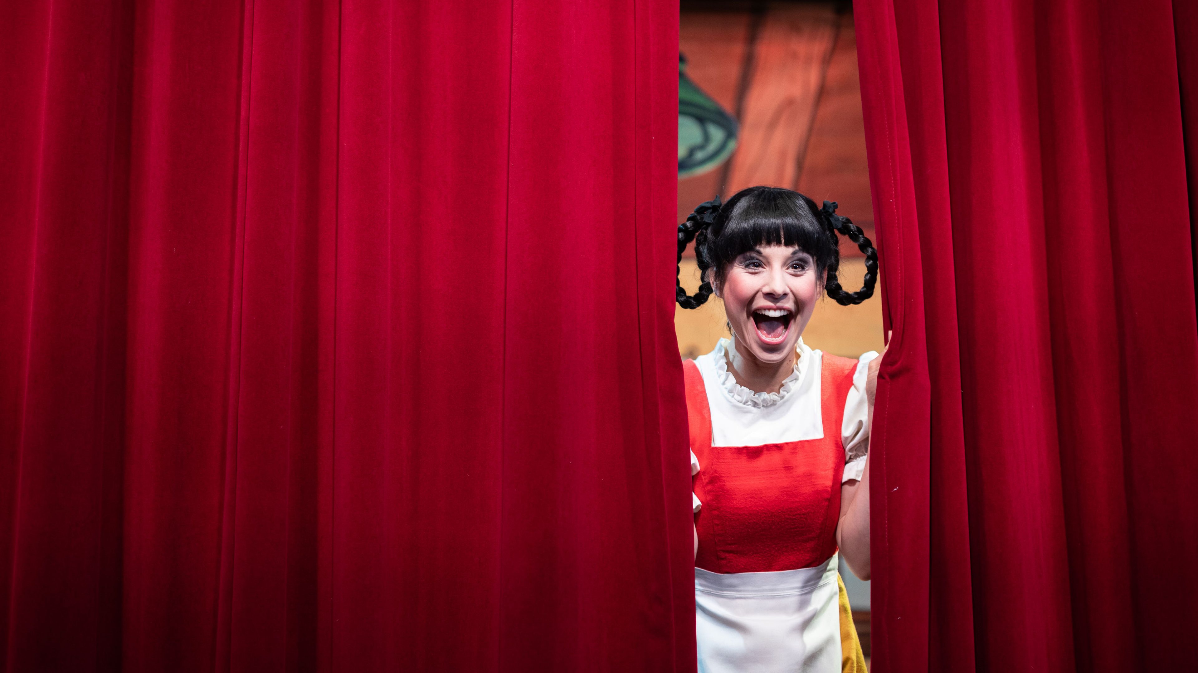 Ramona Fattini guarda attraverso il sipario rosso del teatro in Hechtplatz.