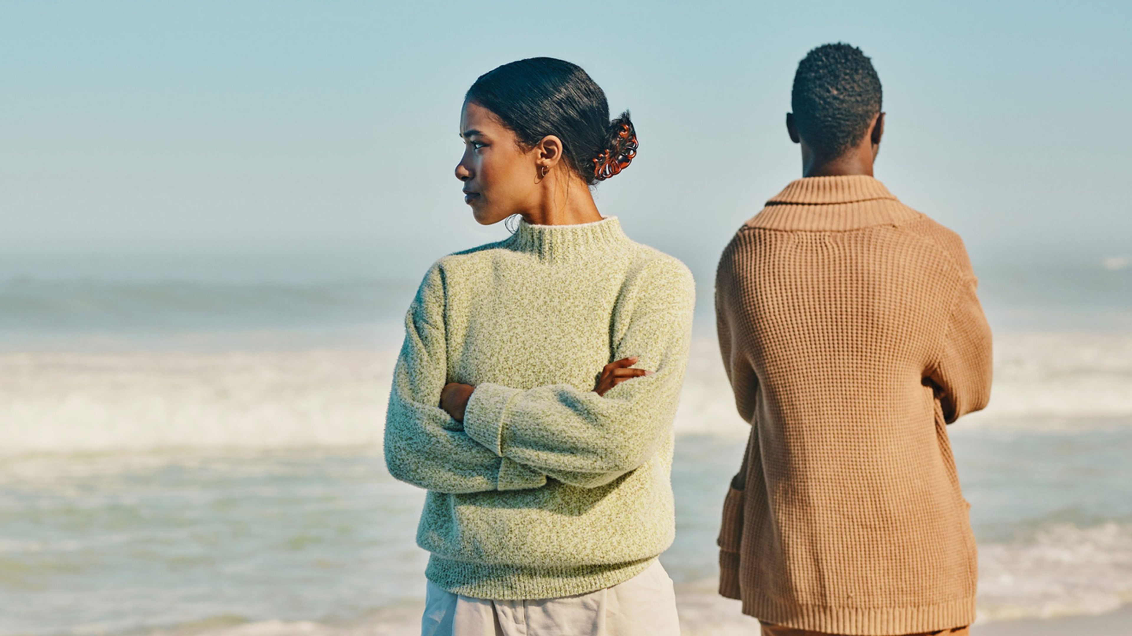 Una coppia si dà le spalle su una spiaggia e i due partner sono arrabbiati l’una con l’altro.