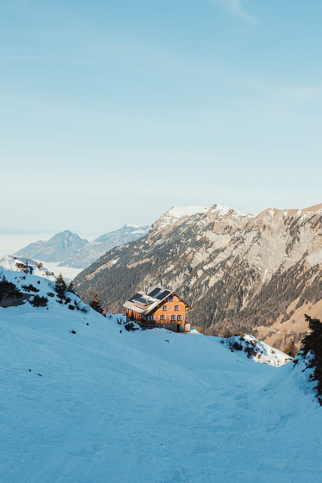 Persona che risale un pendio innevato con gli sci da scialpinismo, circondata da un paesaggio alpino invernale.