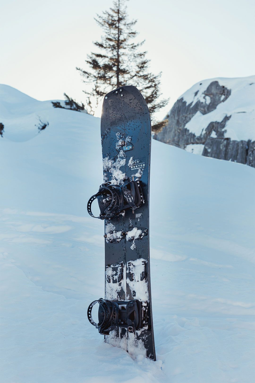 Snowboard nero in controluce nella neve davanti alle Alpi innevate