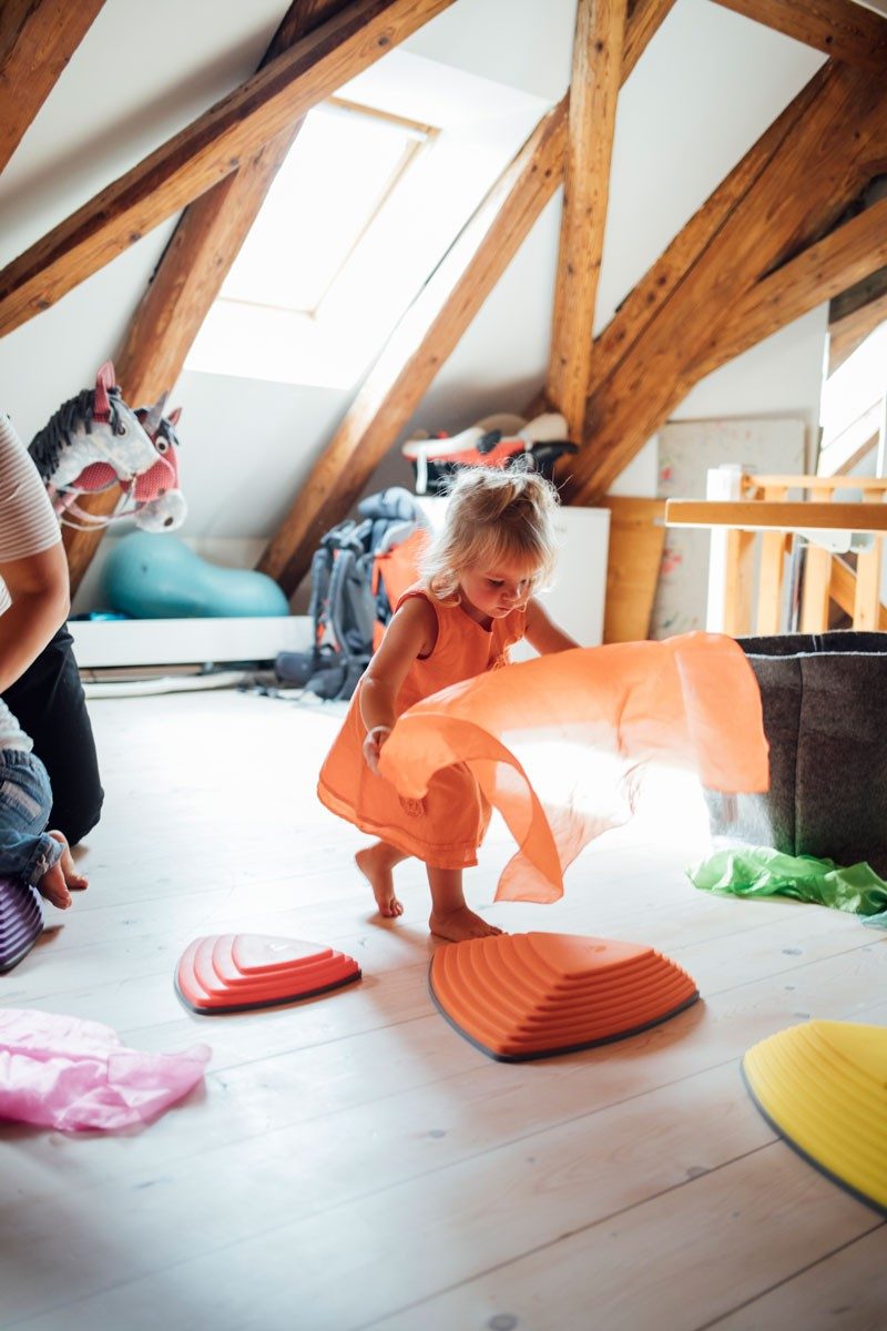 La bambina gioca con un panno arancione.