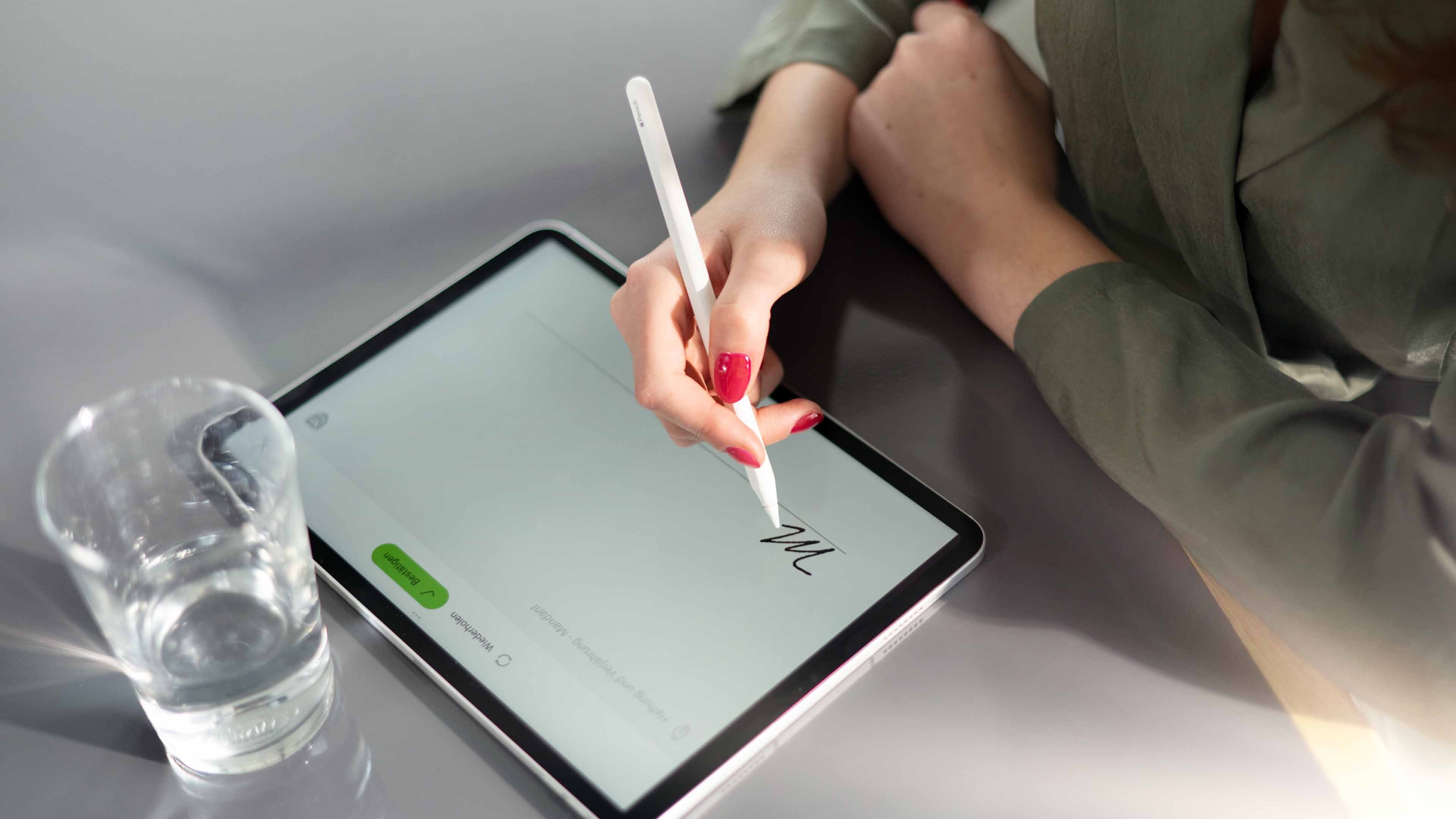 Una donna con le unghie rosse appone la firma digitale sul tablet