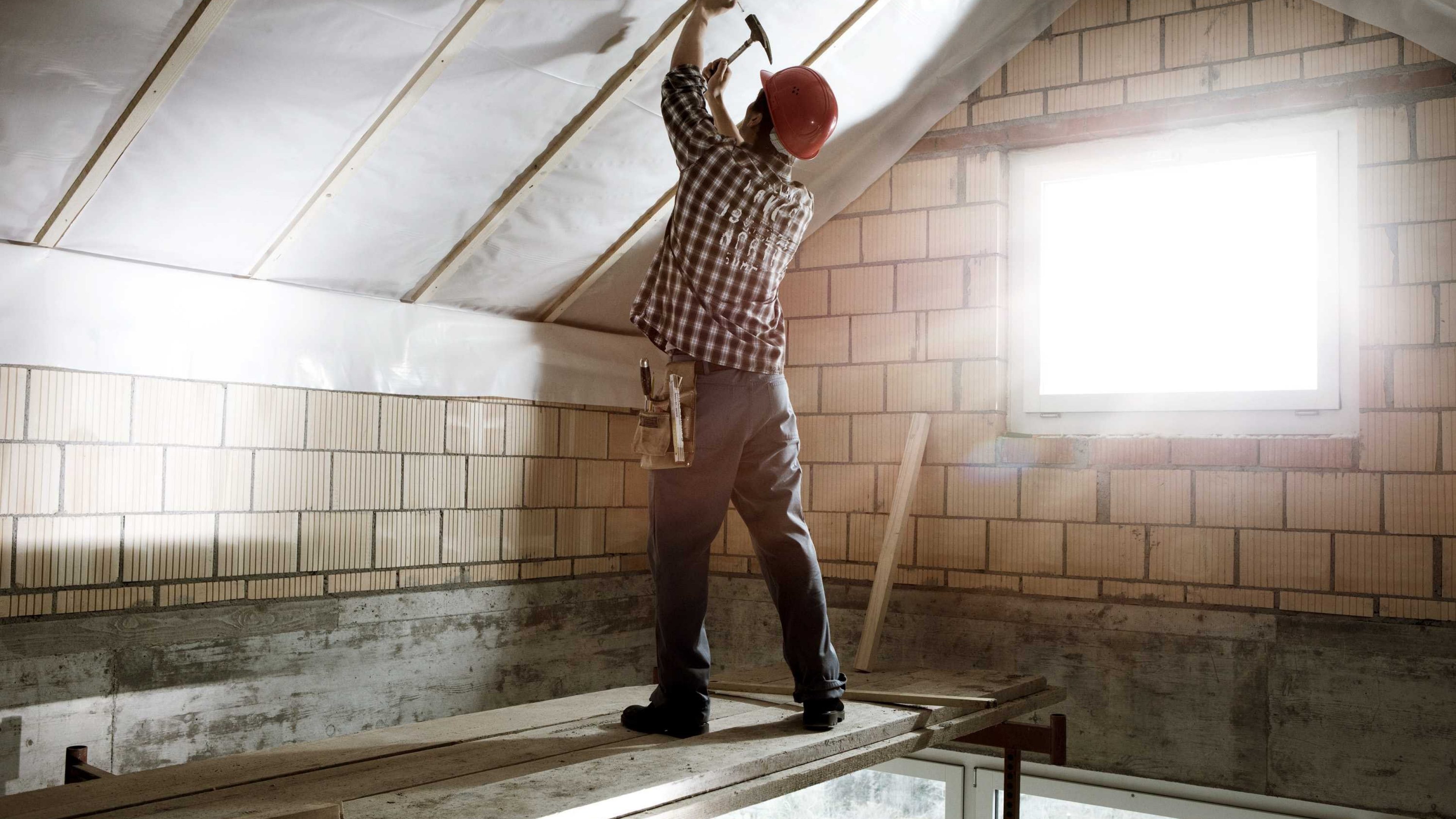Un uomo sta effettuando dei lavori di ristrutturazione al tetto della sua abitazione.