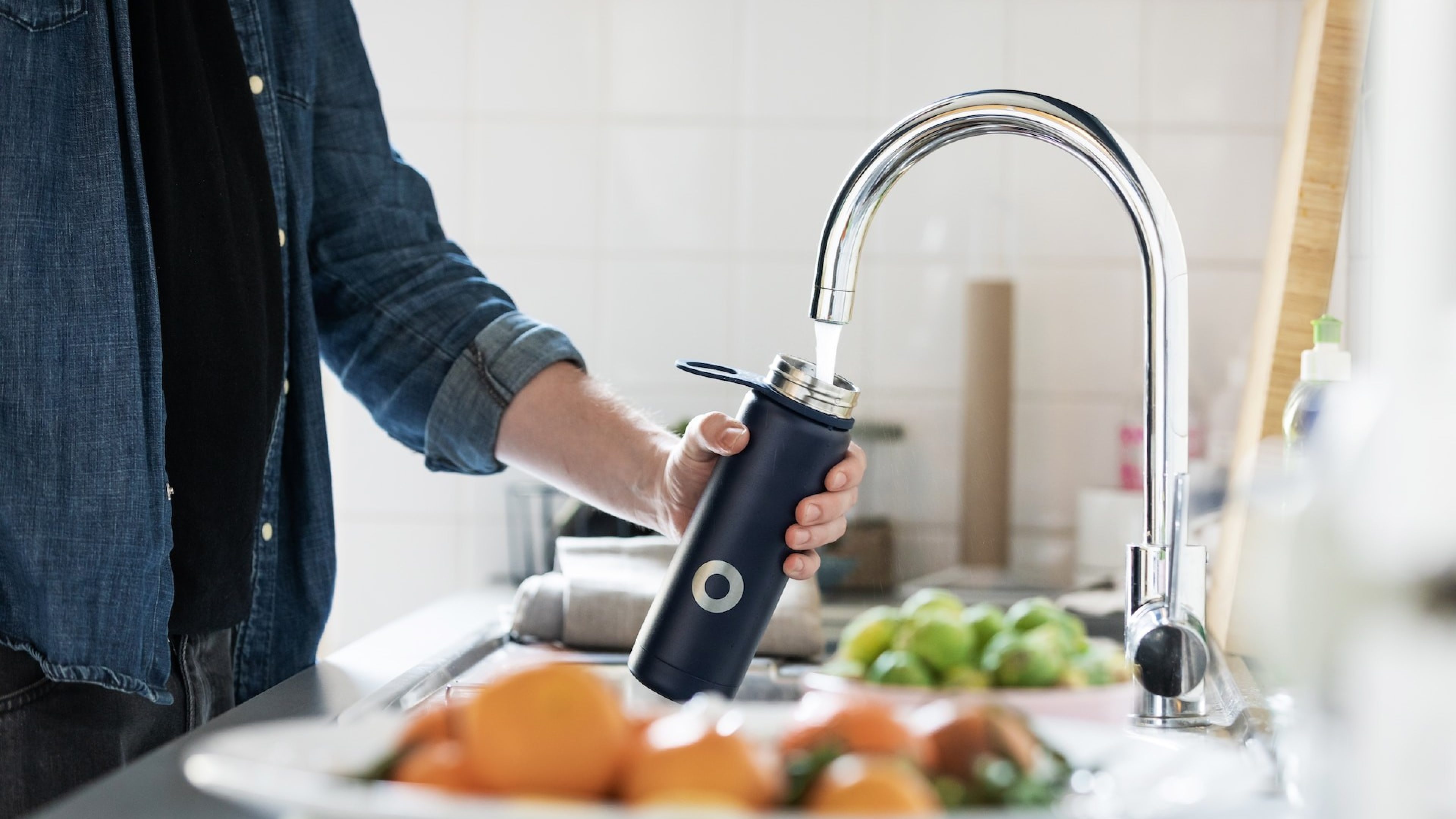 Un uomo riempie la sua bottiglia d’acqua con acqua del rubinetto
