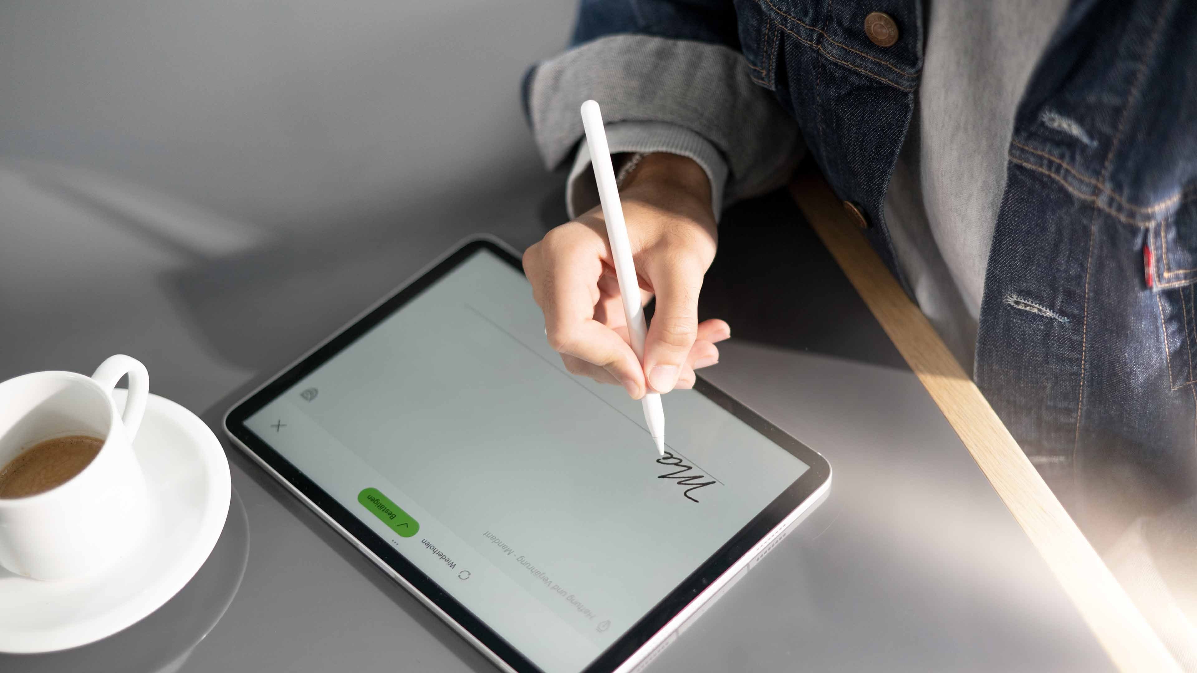 Firma digitale sul tablet e tazza di caffè