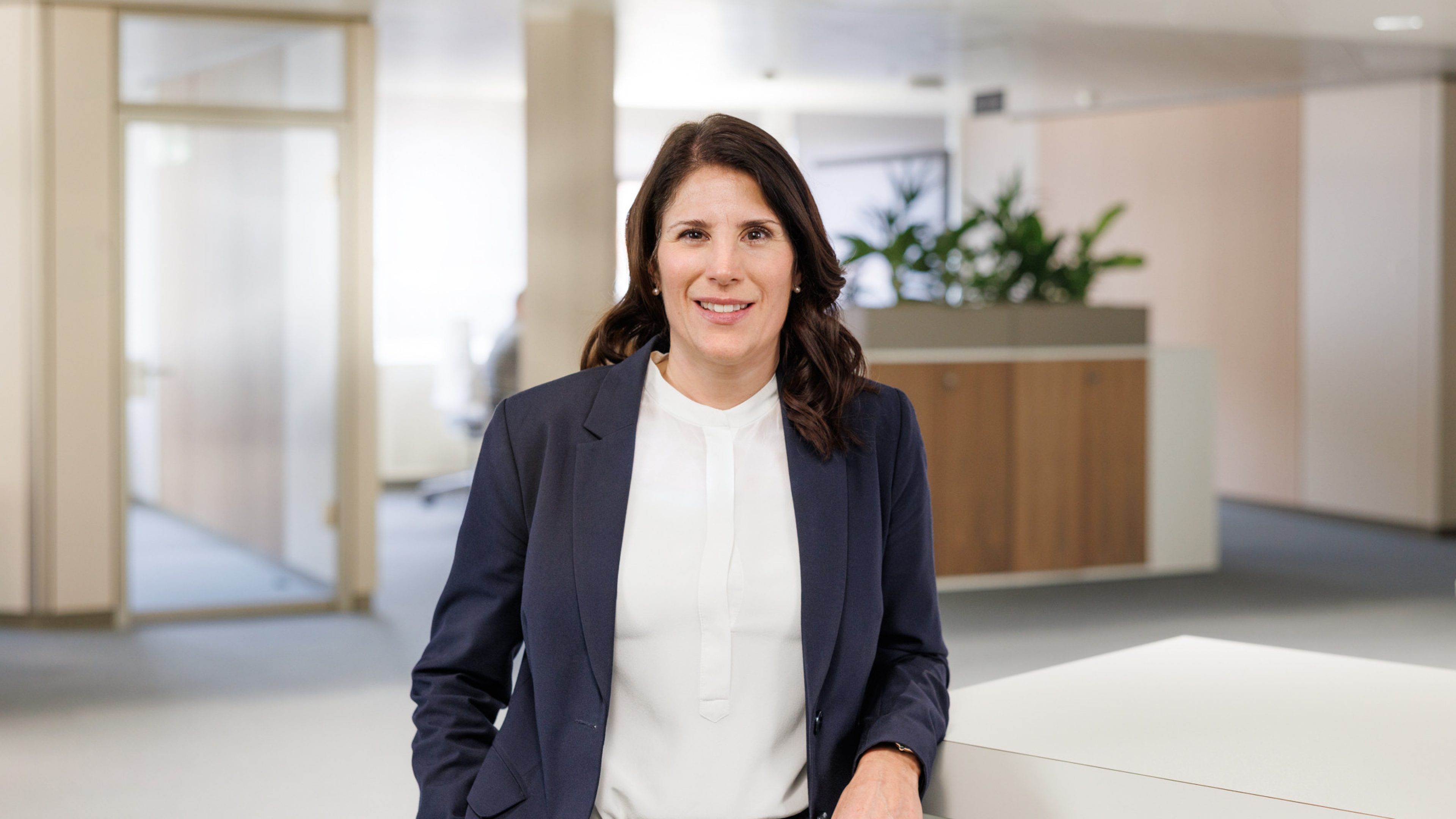 Una collaboratrice di Swiss Life in un ufficio moderno sorride direttamente all’obiettivo.