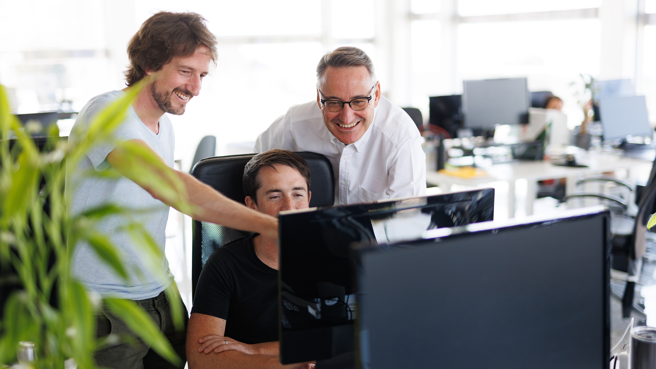 Ein Bild von Luiggino Torrigiani, einem Startup-Berater, der in einem Büro an einem Tisch vor einem Computer mit zwei Jungunternehmern steht und sie berät. Das Bild zeigt eine professionelle Arbeitsumgebung und symbolisiert den Rat und die Unterstützung, die Luiggino als Berater den jungen Unternehmern bietet.