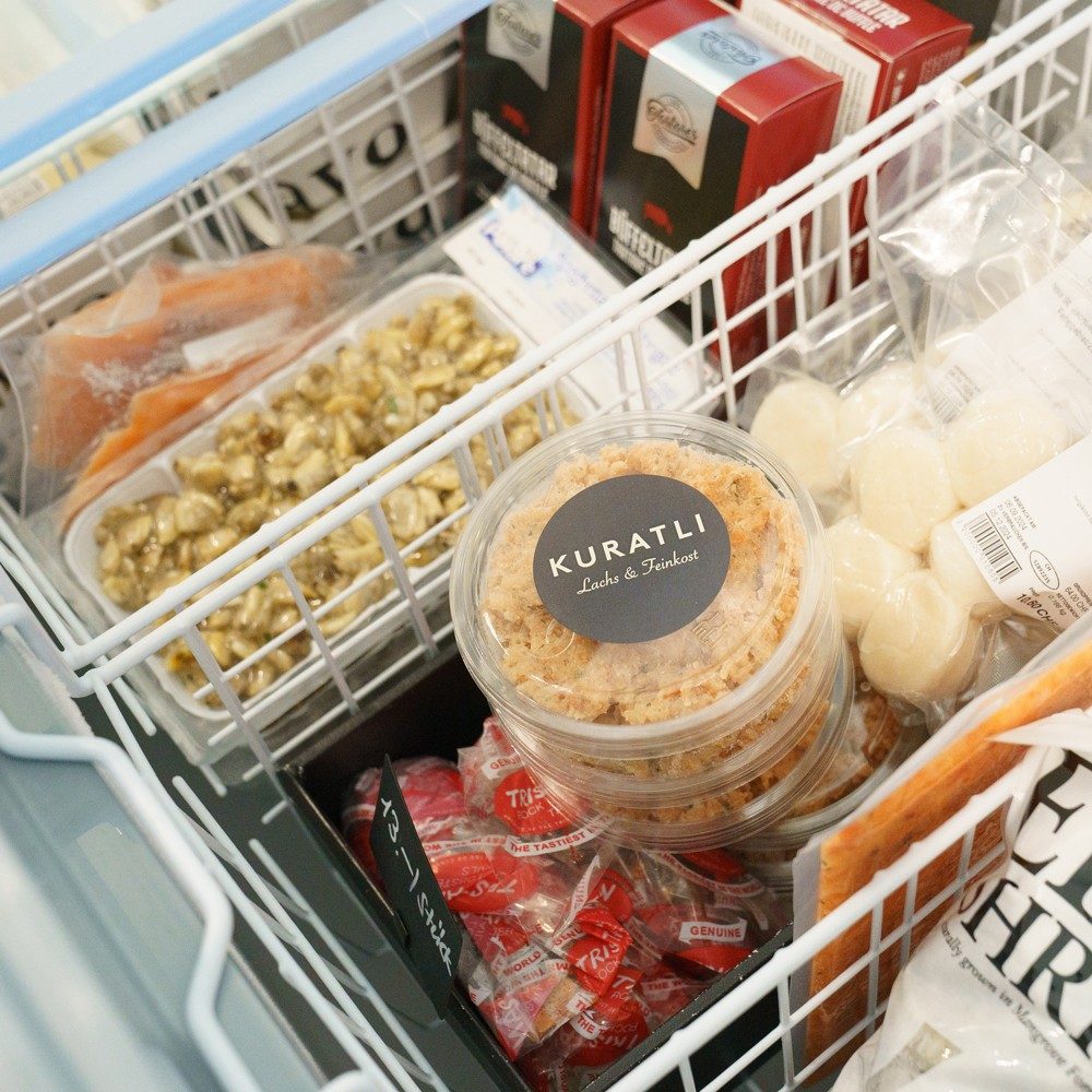 Vista su un congelatore, in cui sono riposti diversi prodotti frigoriferi. Salta all’occhio un contenitore di plastica con la scritta «Kuratli».