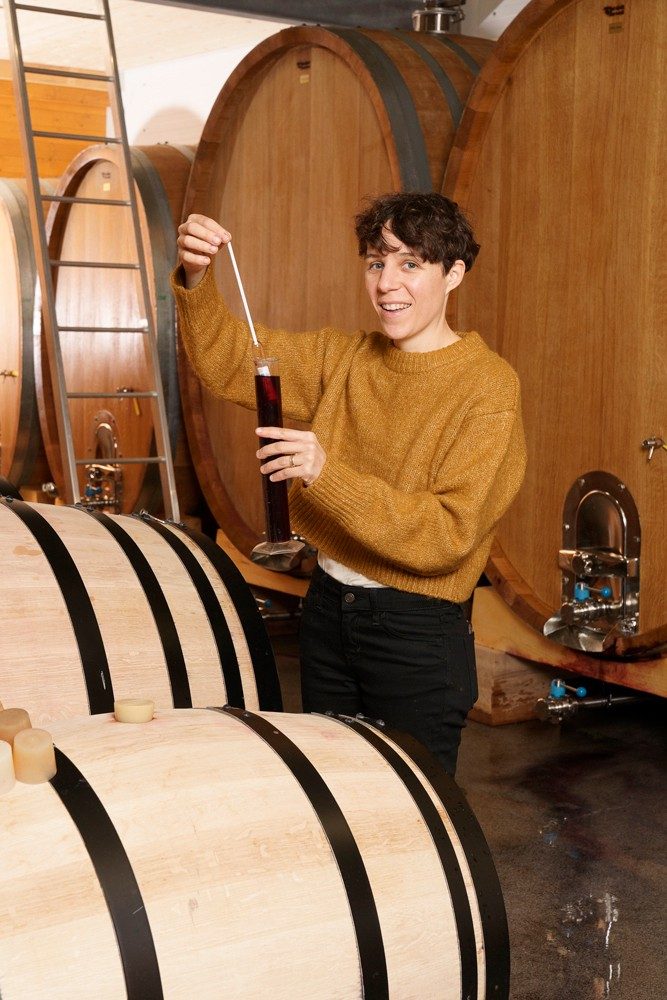 Una donna sorridente che pipetta il vino.